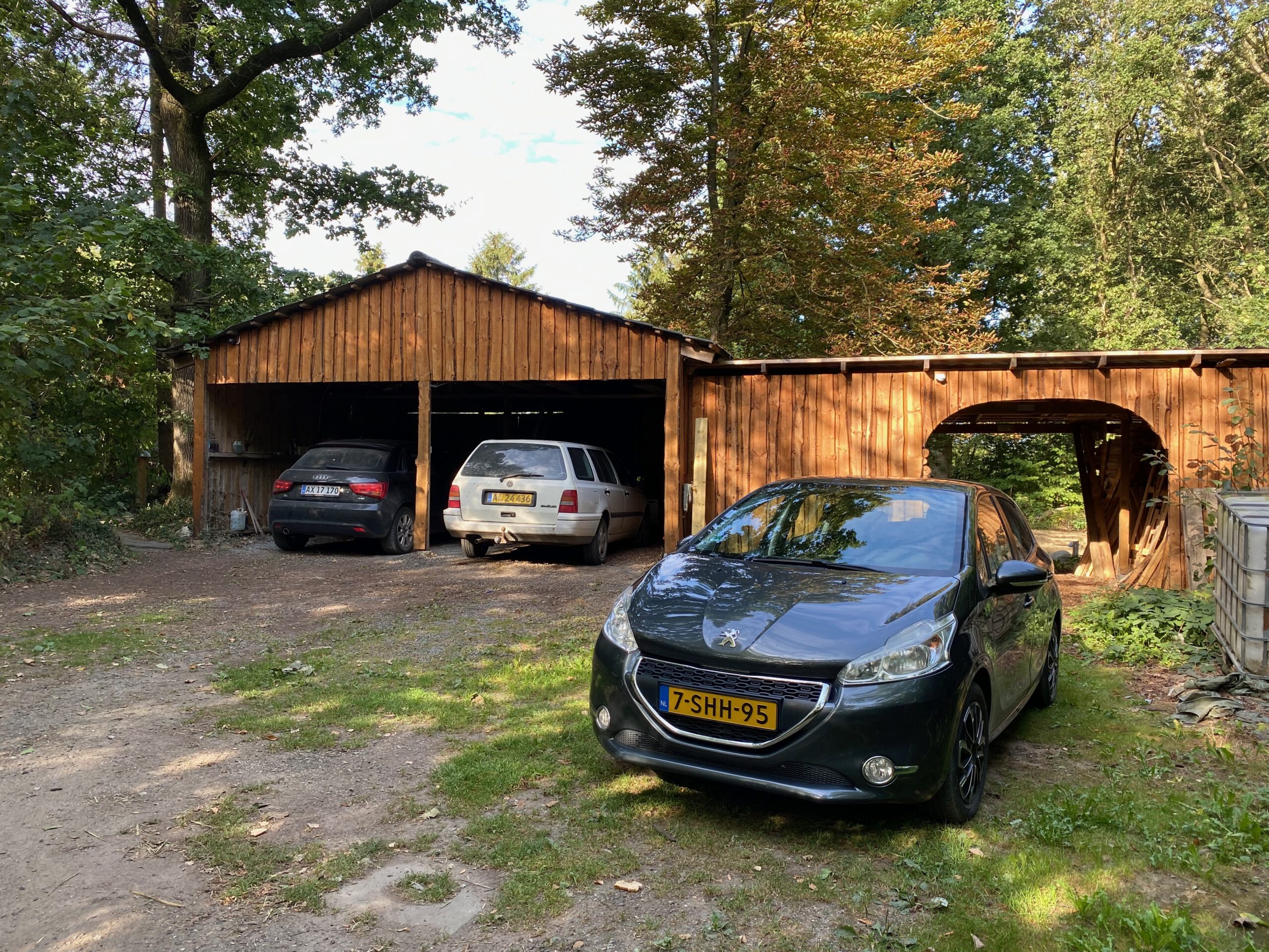 Solevad Cottage in the Forest, Timobiel the Peugeot 208 from 2013 parked on a forest driveway near the wooden buildings in Denmark
