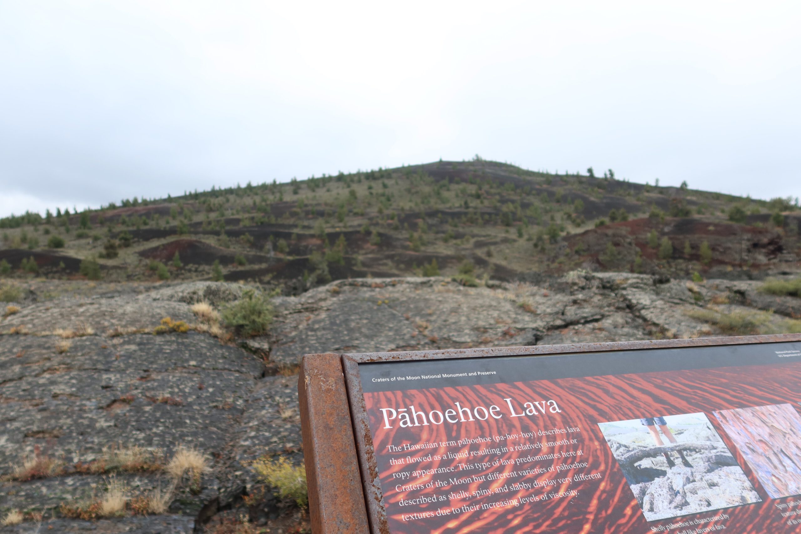 Pāhoehoe lava information sign at Craters of the Moon National Monument in Idaho, with volcanic landscape and lava flows in the background