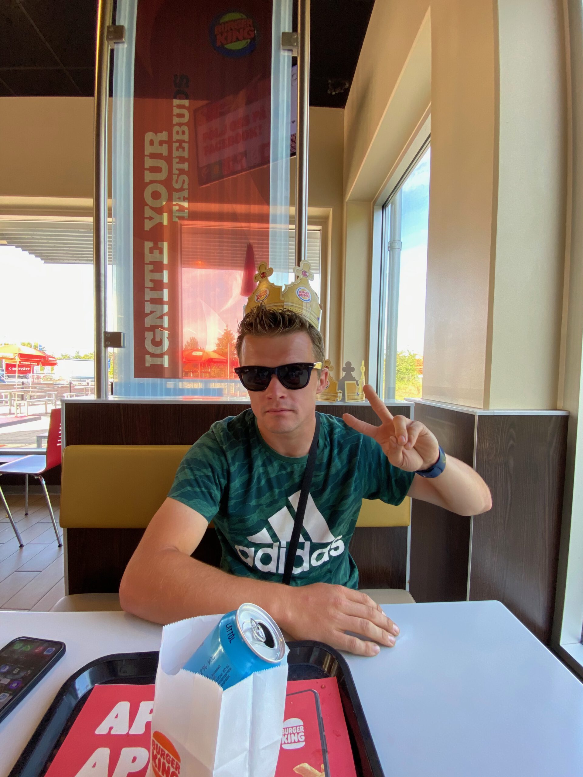 Burger King Malmö Ollebo interior with Peter Smit wearing a Burger King crown, sitting at a table during a relaxed road trip stop in Sweden