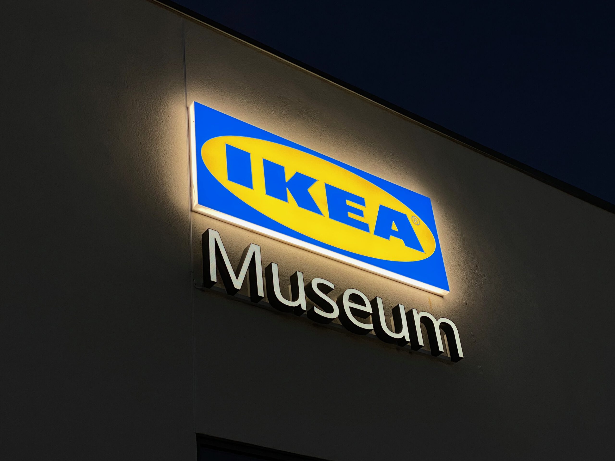 IKEA Museum Älmhult exterior at night, illuminated IKEA logo on the museum building in Sweden