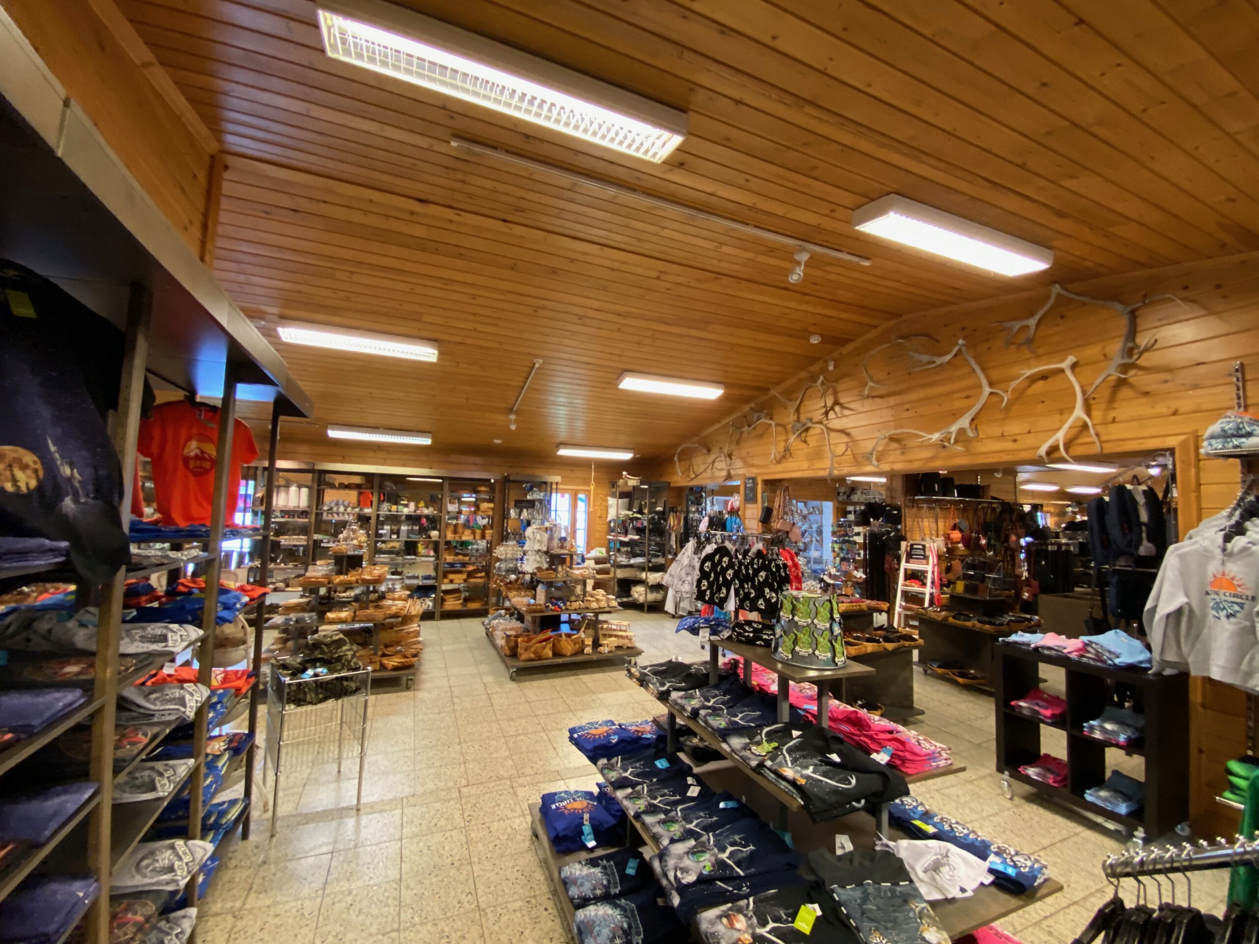 Arctic Circle Tuomaan Tupa Finland, interior view of the spacious souvenir shop in Juoksenki, Lapland, showcasing Arctic themed clothing, Sami inspired products, wooden interior design, and a cozy road trip shopping experience