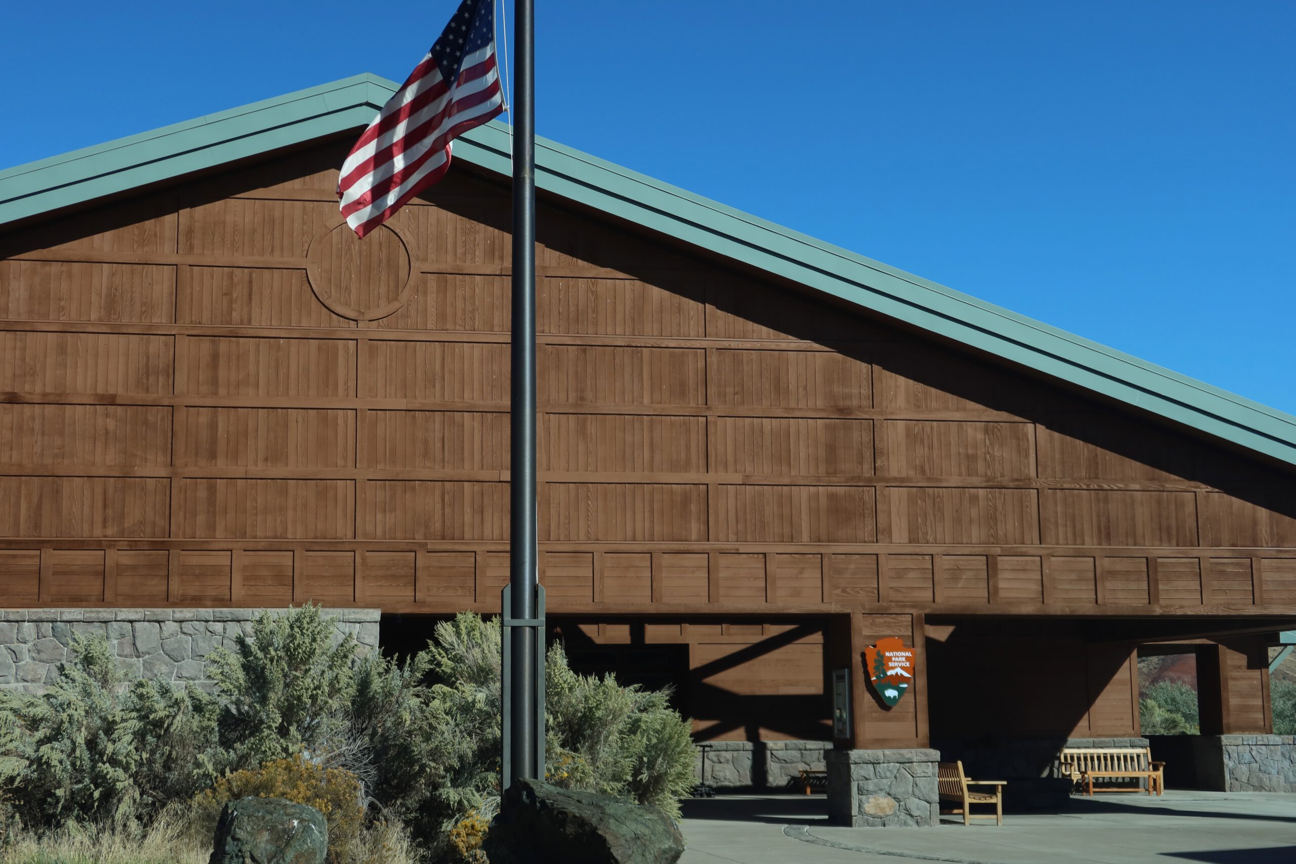 John Day Fossil Beds National Monument visitor center exterior with wooden architecture and American flag under a clear blue sky in Eastern Oregon
