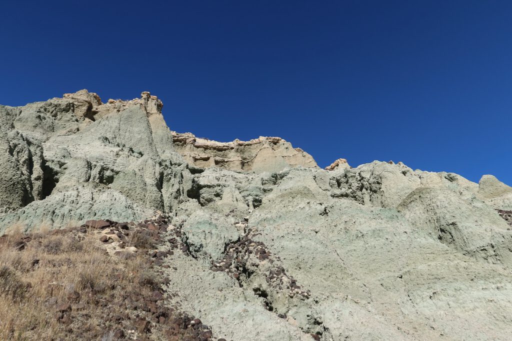 Eroded green clay badlands and volcanic ash layers at John Day Fossil Beds National Monument, showing steep formations formed by millions of years of erosion in Eastern Oregon