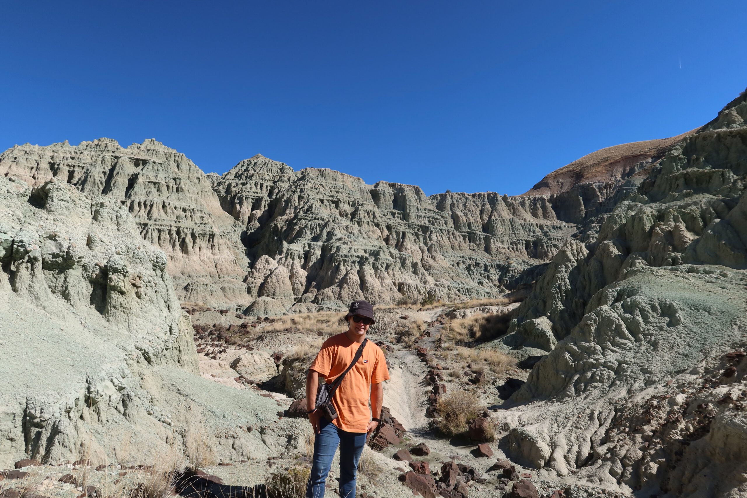 AltijdPeter, Peter Smit, hiking through rugged badlands at John Day Fossil Beds National Monument, walking along a trail surrounded by layered volcanic rock formations in Eastern Oregon