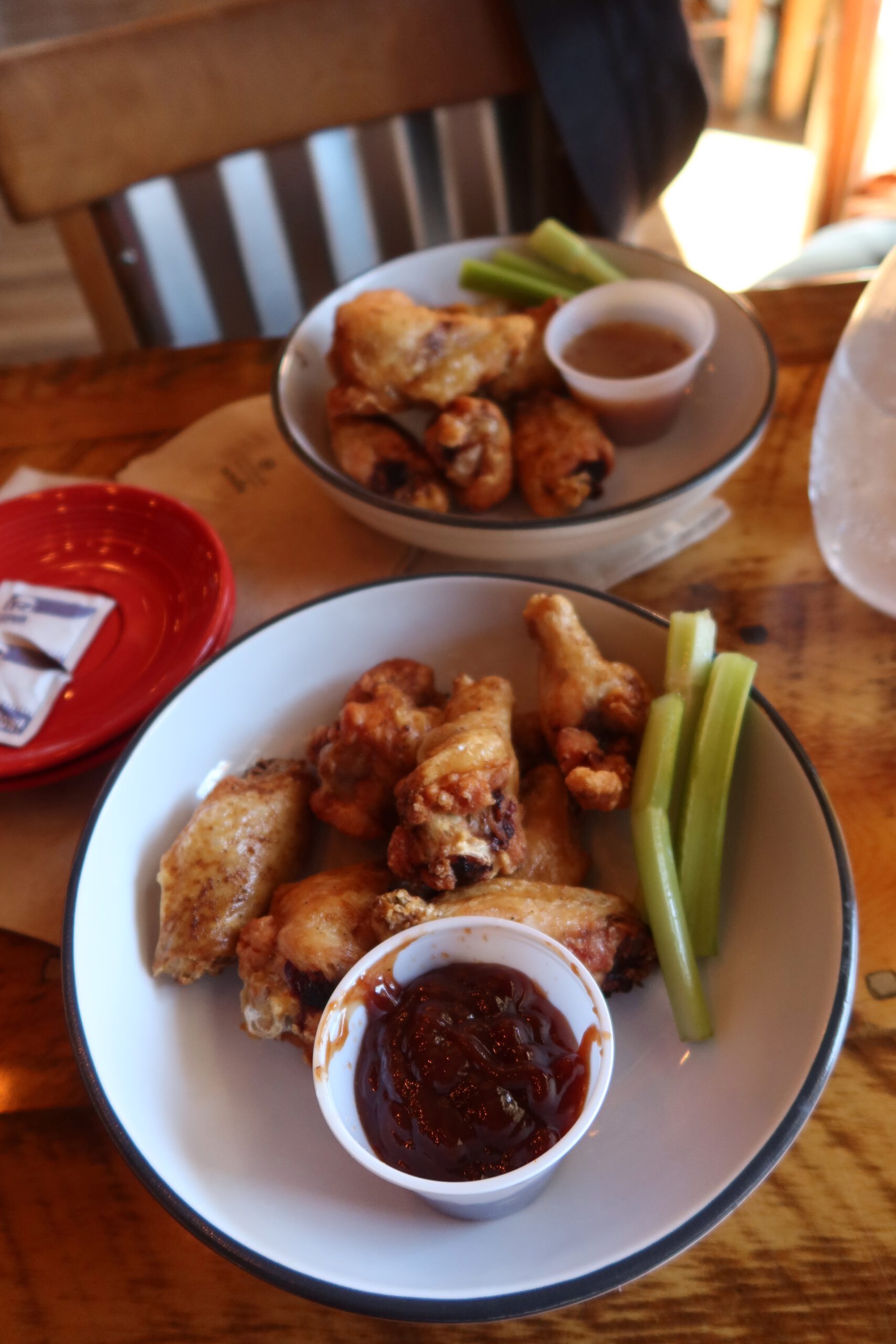 Plate of crispy chicken wings served with celery sticks and dipping sauce at 1188 Brewing Company in John Day Oregon, photographed on a wooden table inside a cozy small town brewery restaurant.,