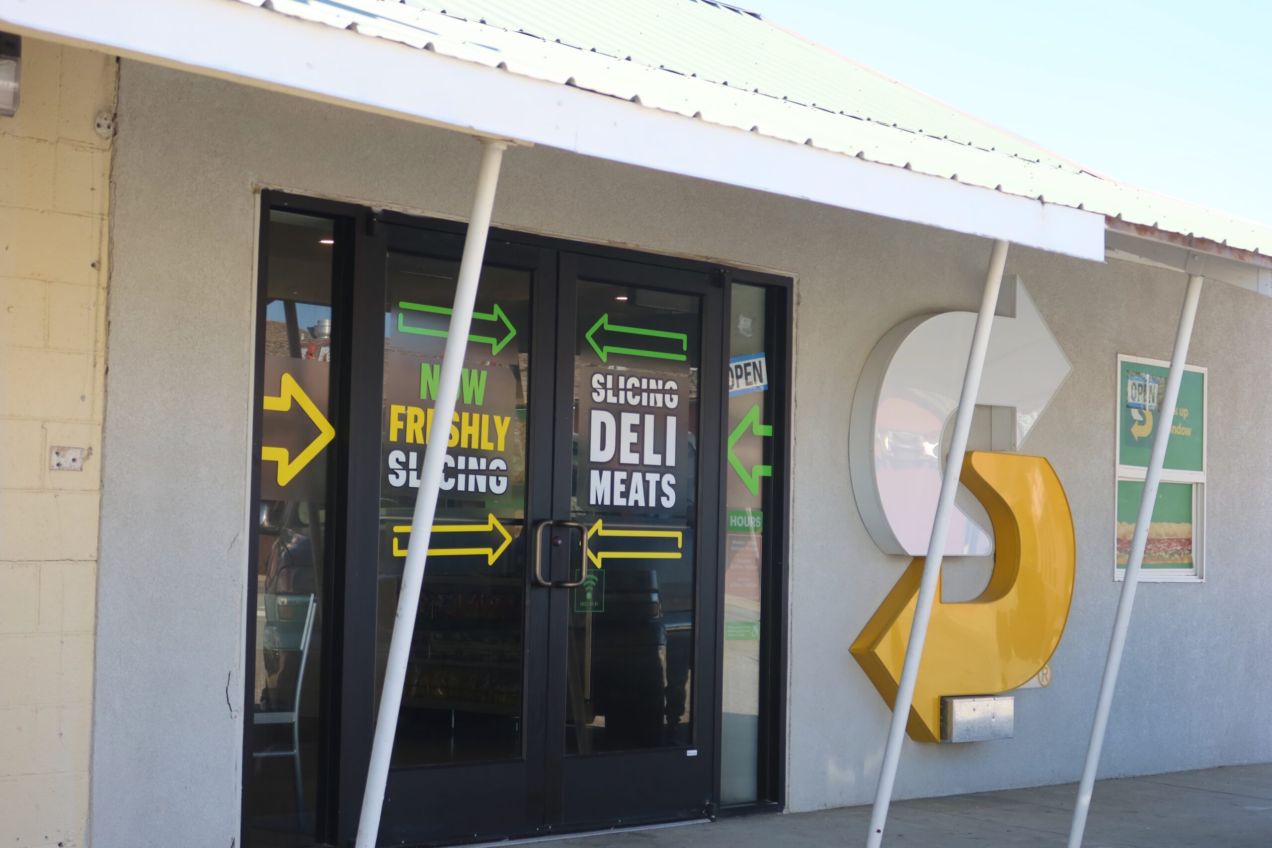 Exterior entrance of Subway restaurant in McDermitt Nevada with branded doors, fresh deli meats signage, and iconic yellow Subway logo along US Highway 95