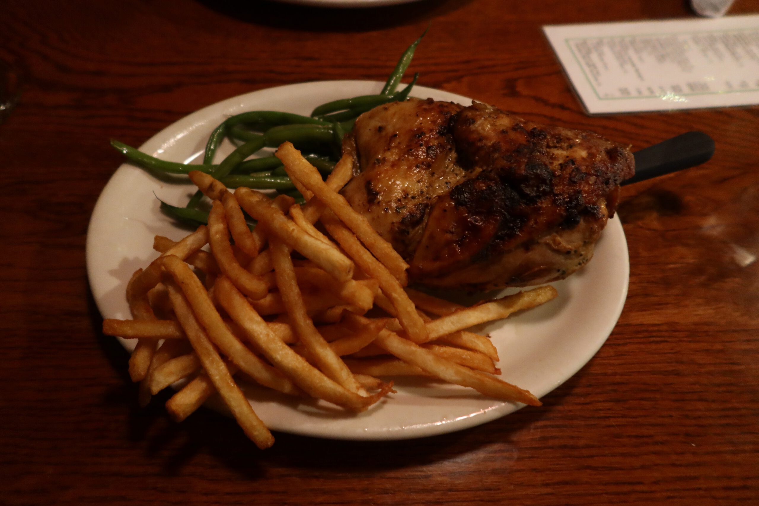 Grilled chicken dish served at Jasons Beachside Grille Lake Tahoe with French fries and green beans on a white plate during dinner in Kings Beach, California.