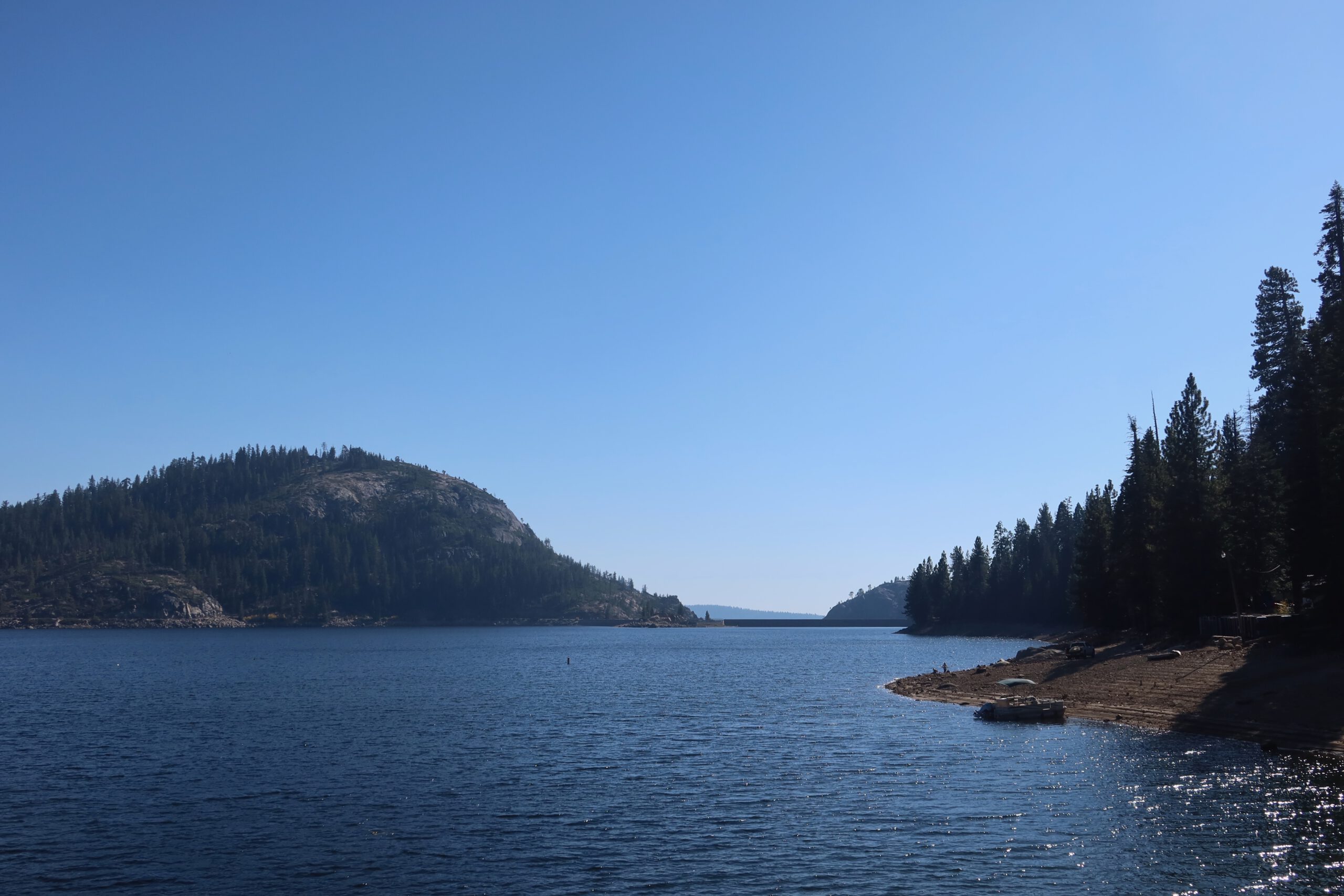 Wide view over Bear River Lake in the Sierra Nevada, California, with calm blue water, forested granite hills, and a clear summer sky near Bear River Lake Resort