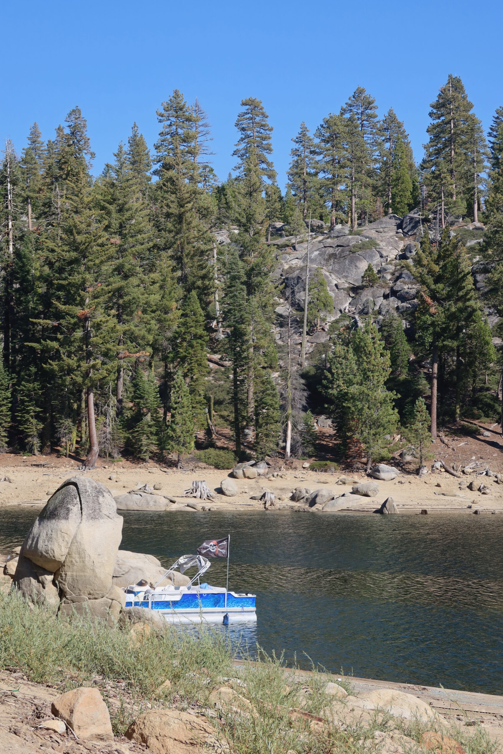 Quiet shoreline view of Bear River Lake near Bear River Lake Resort in Amador County, California, with a small boat on the water and forested Sierra Nevada hills