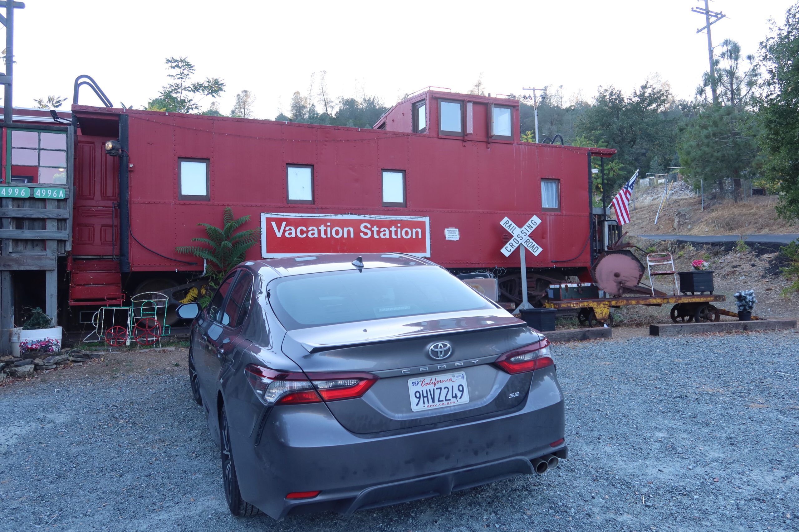 Toyota Camry 2024 with California license plate parked in front of Vacation Station Coulterville, red caboose Airbnb near Yosemite National Park