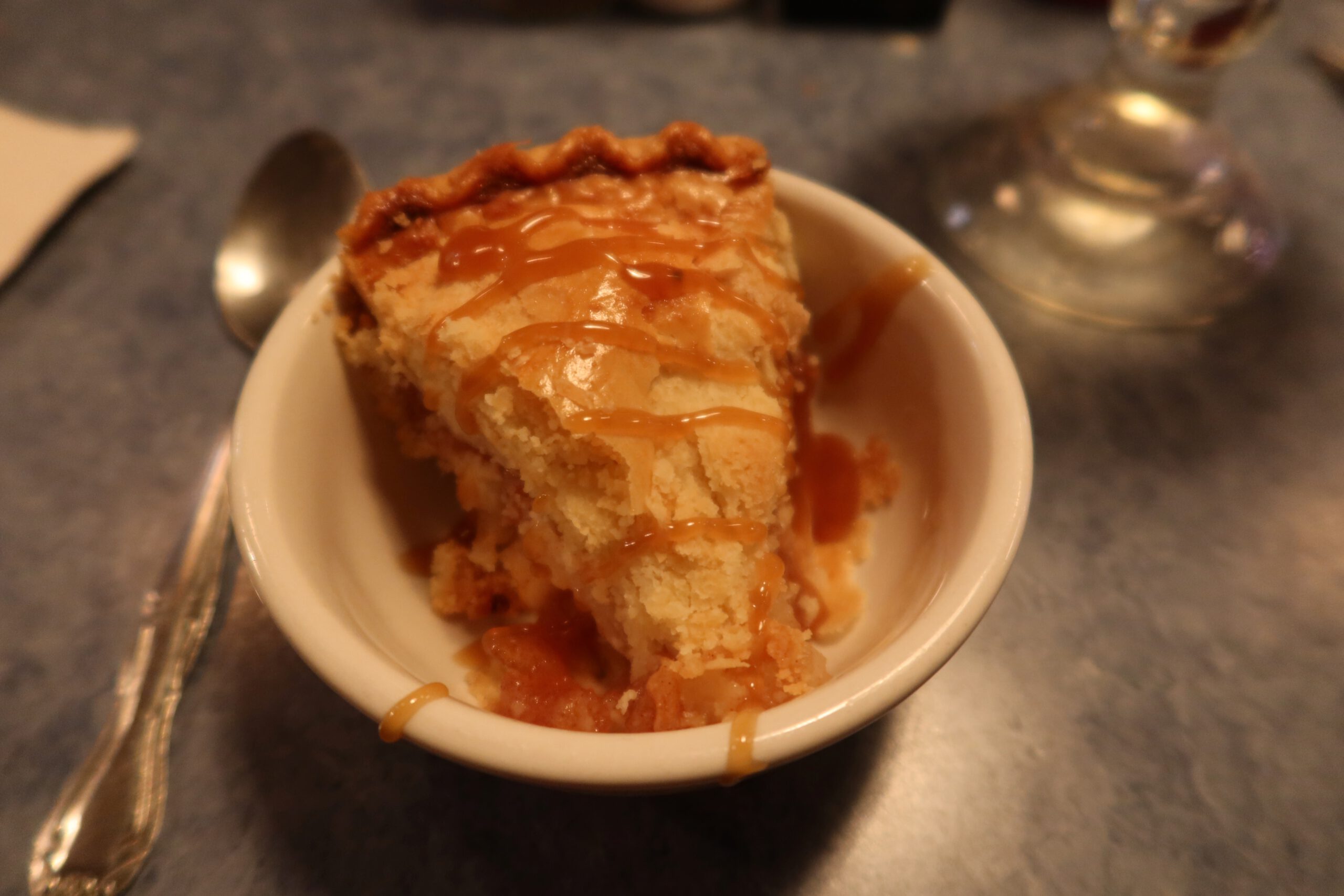 Apple pie dessert at Lucky Buck Cafe California, served warm in a small bowl with caramel sauce, classic American diner dessert near Yosemite and Highway 120.