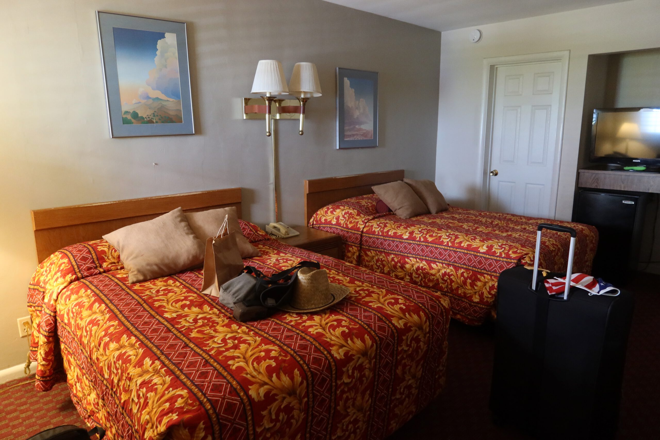 Town House Motel San Francisco room interior with two double beds, vintage patterned bedspreads, classic motel decor, luggage in room, showing a clean but dated motel room