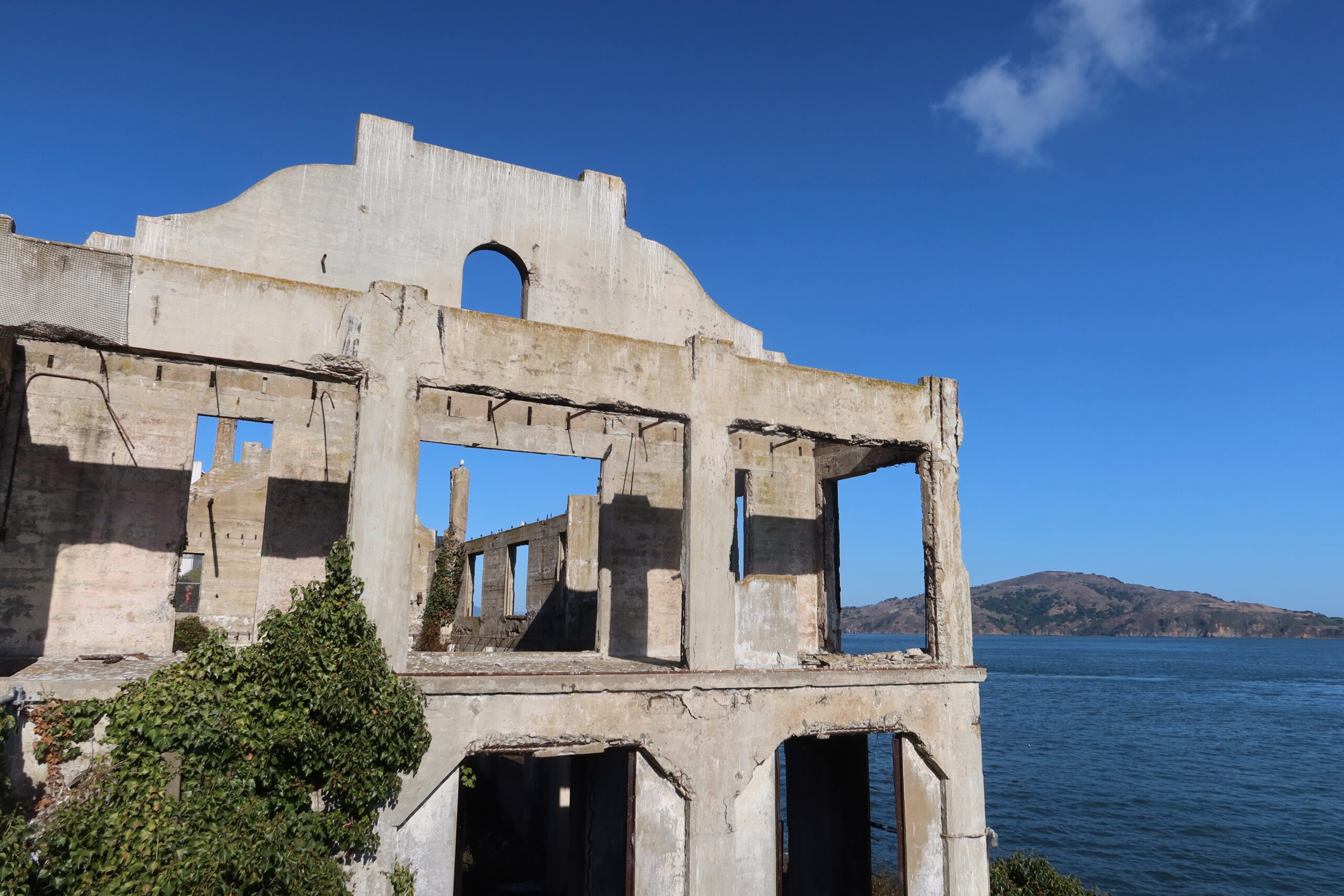 Historic Alcatraz Island ruins with arched concrete facade and ivy growth, overlooking the waters of San Francisco Bay