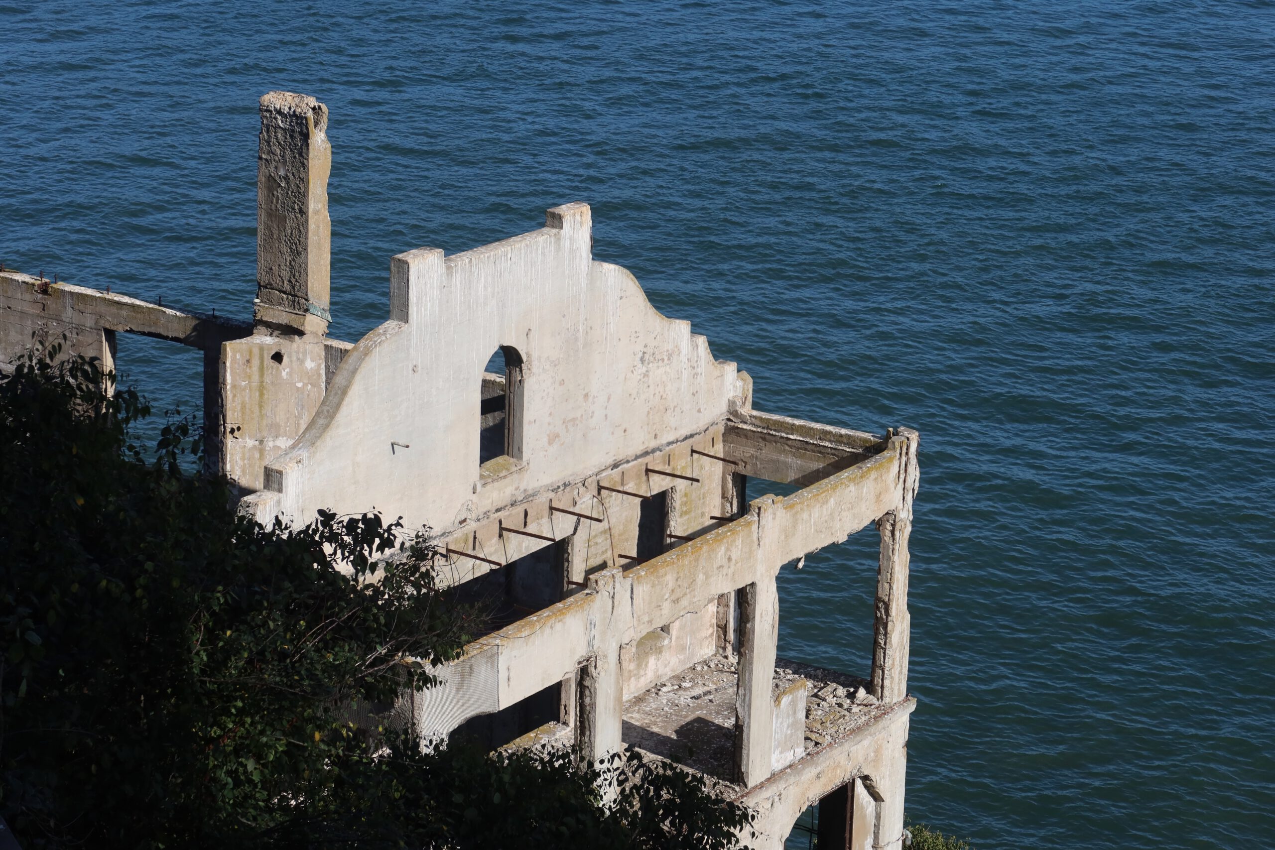 Ruins of former Alcatraz Island industrial building overlooking San Francisco Bay, concrete walls and foundations standing above the water