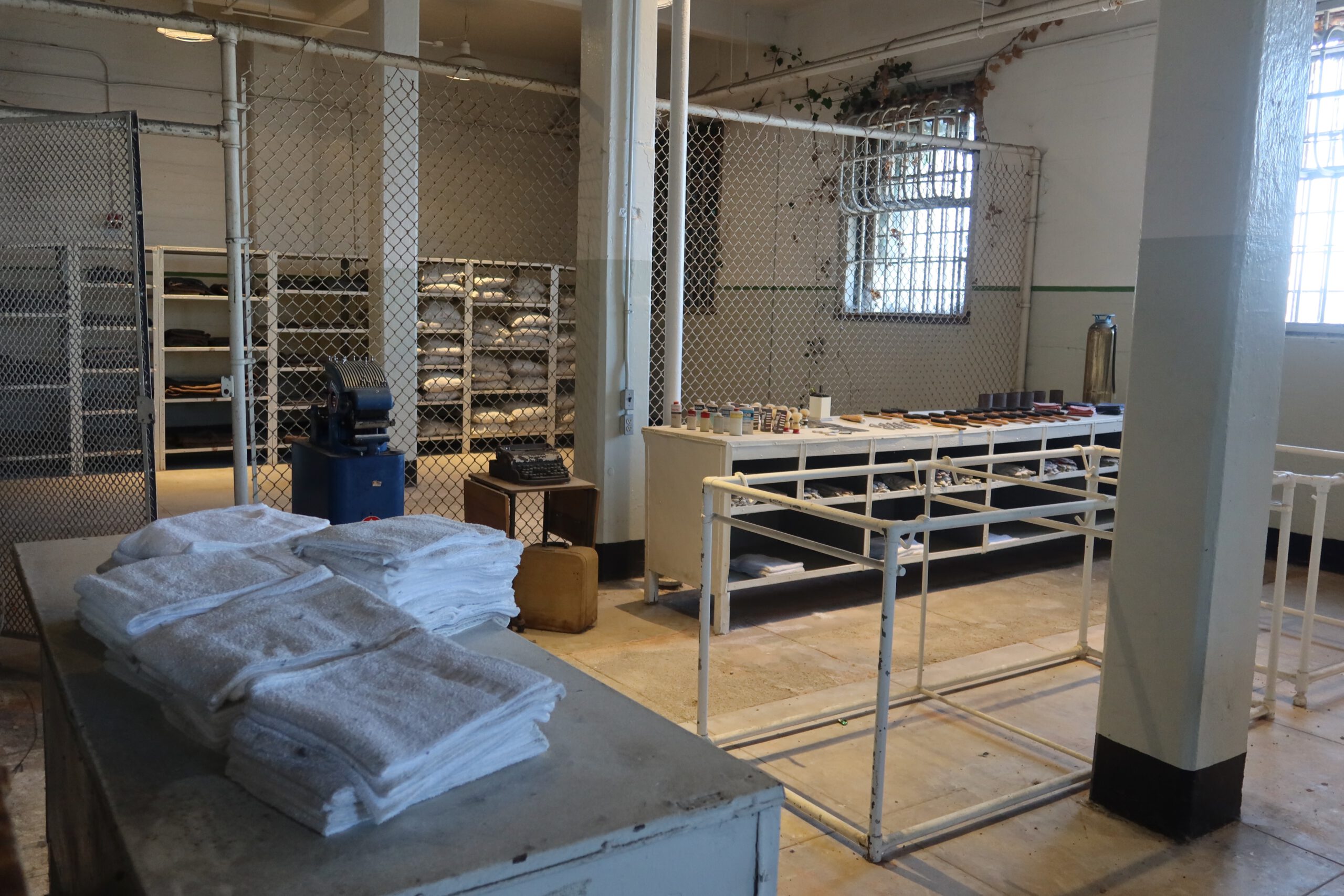 Former laundry and storage area on Alcatraz Island with folded towels, work tables, shelving and secured fencing