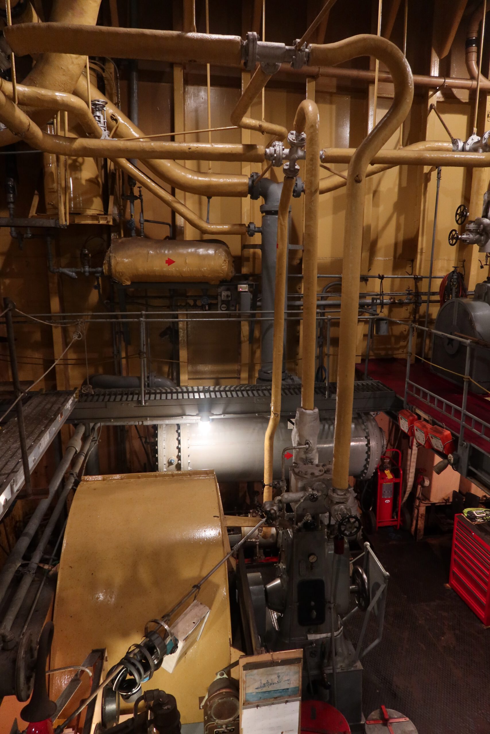Detailed view of valves, insulated pipes, and control systems in the SS Jeremiah O’Brien engine room, preserved World War II naval engineering.