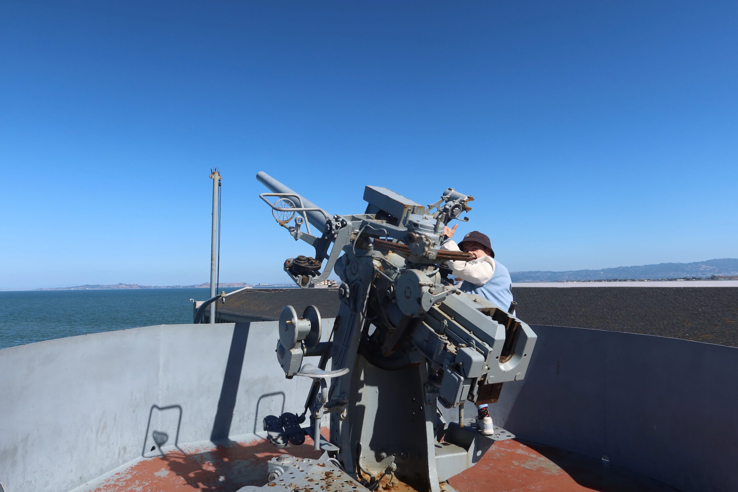 SS Jeremiah O'Brien restored World War II deck gun with visitor interaction, highlighting authentic naval defense equipment aboard the historic Liberty ship