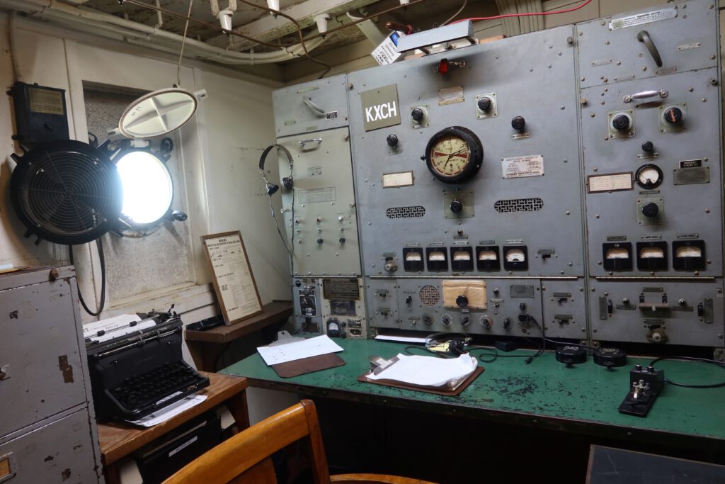 Historic radio and operations room on the SS Jeremiah O'Brien San Francisco with analog gauges, control panels, typewriter, and original maritime communication equipment.