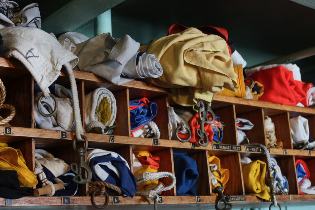 Signal flags and rope lines neatly stored in wooden compartments aboard the SS Jeremiah O'Brien San Francisco, showcasing authentic World War II naval equipment below deck.