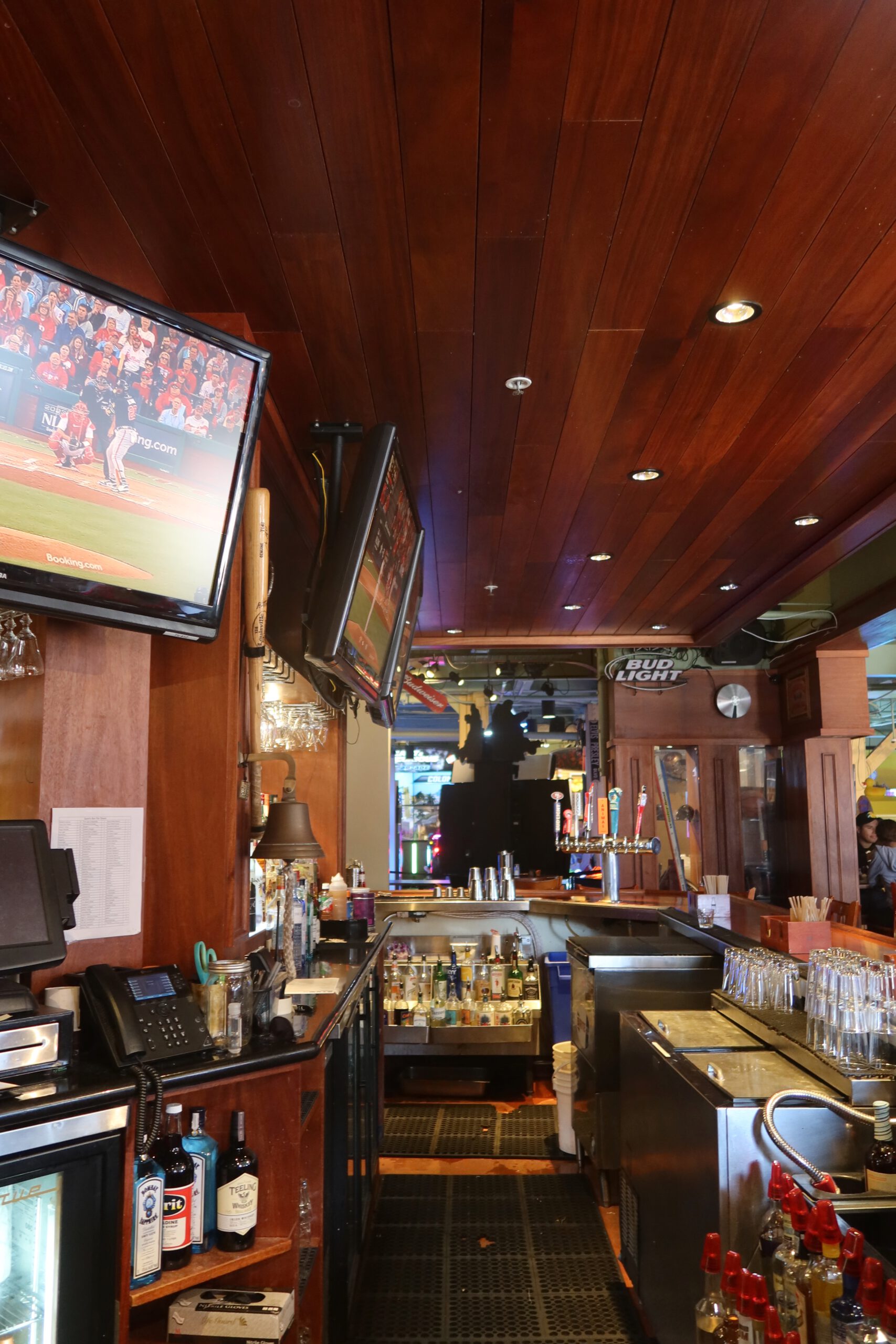 Interior bar at Players Sports Grill & Arcade on Pier 39 in San Francisco, showing beer taps, liquor bottles, Bud Light signage, multiple TV screens with live sports, and a classic American sports bar atmosphere.