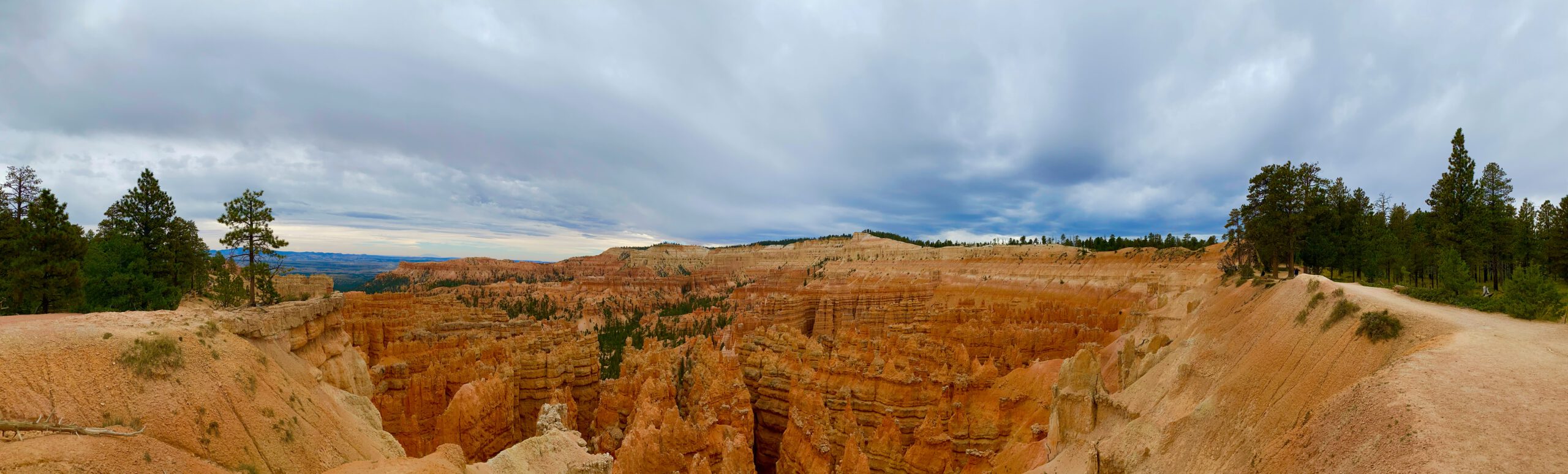 Panoramic view of Bryce Canyon National Park showing vast orange hoodoos, layered canyon walls, and dramatic skies over Utah’s iconic landscape