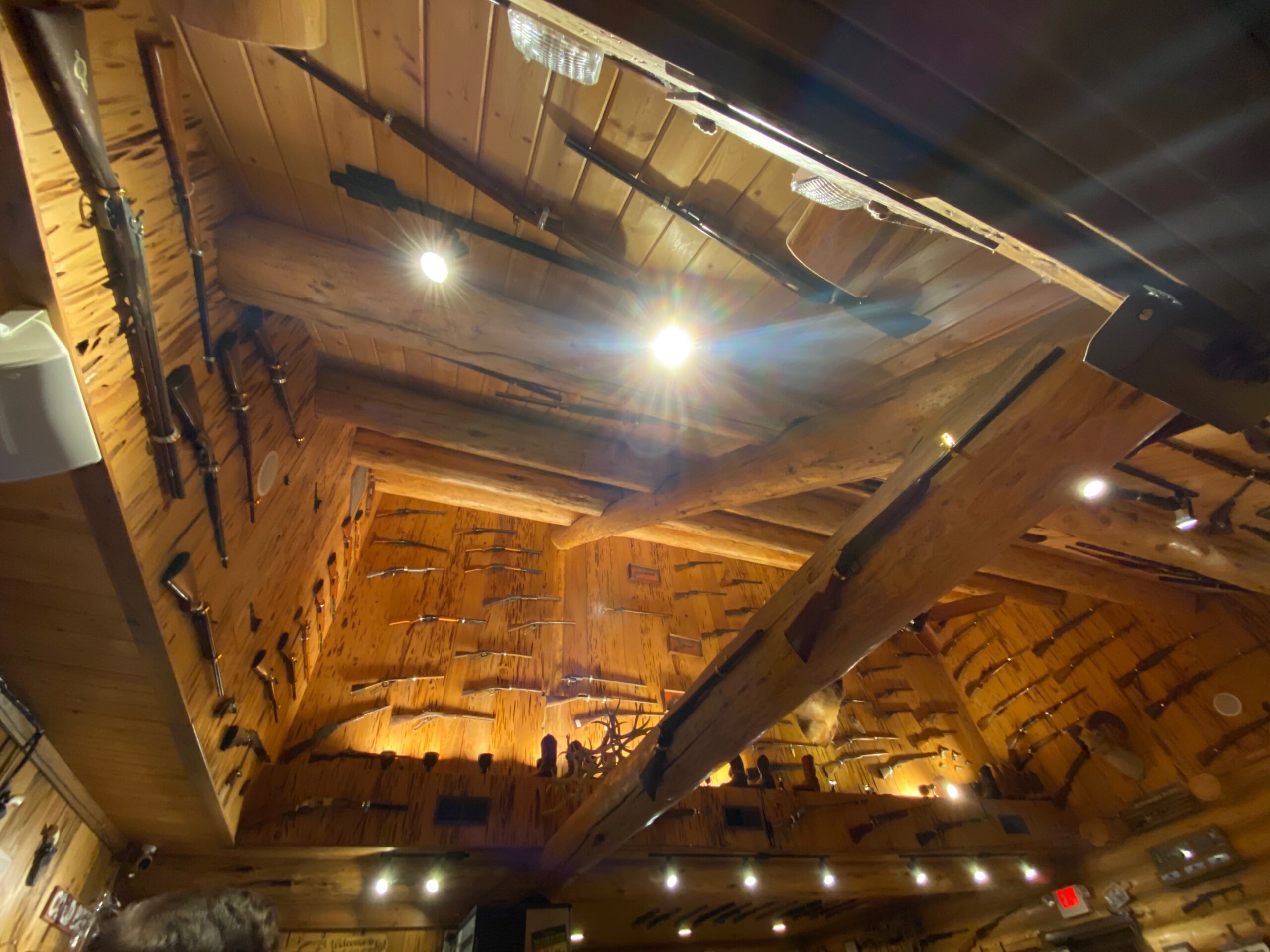 Warm wooden lodge interior filled with historic rifles and Western memorabilia at Cowboy’s Lodge and Grille Gardiner Montana