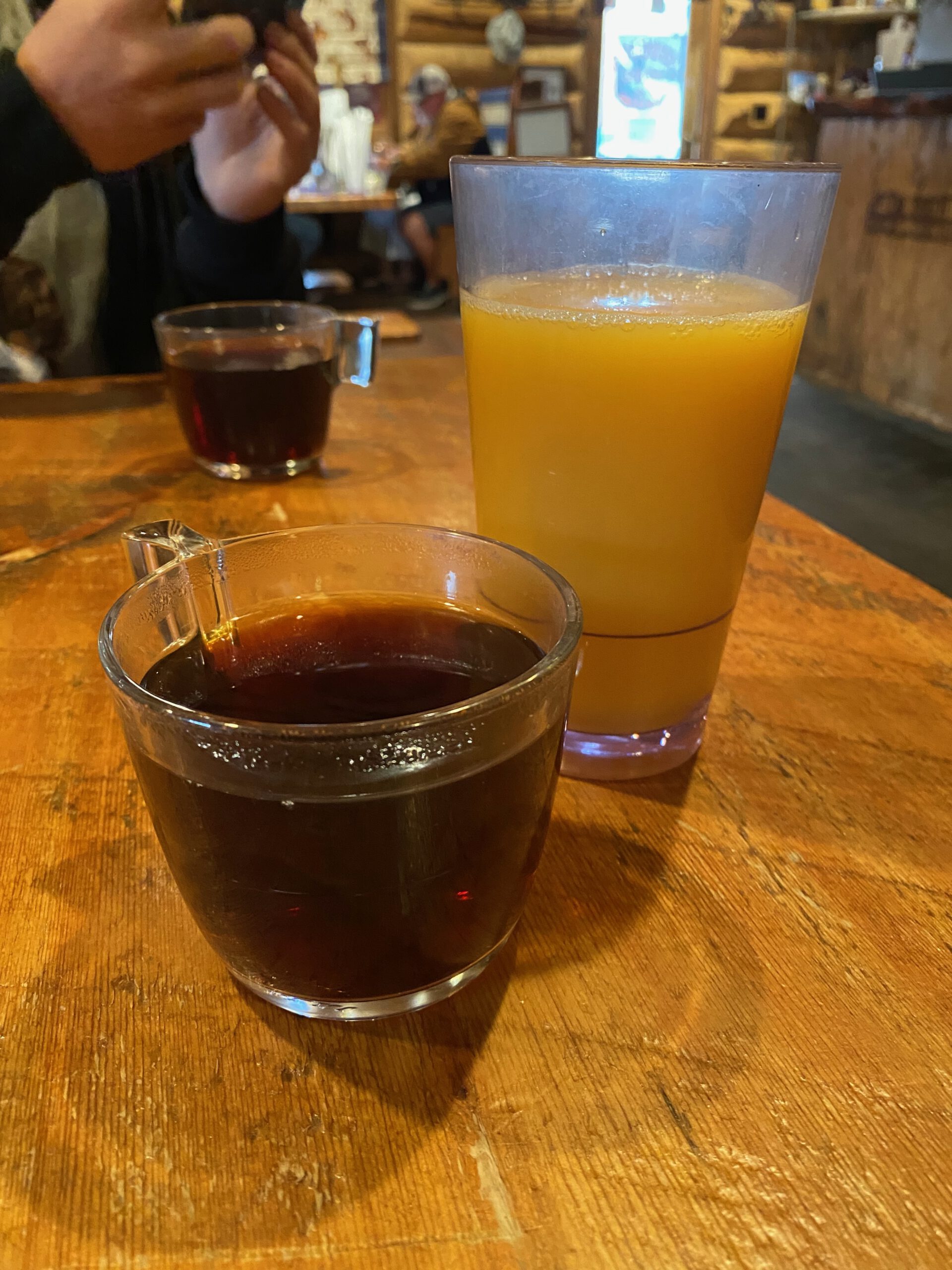 Freshly brewed coffee and orange juice on a wooden table at Cowboy’s Lodge and Grille Gardiner, popular breakfast stop near Yellowstone National Park