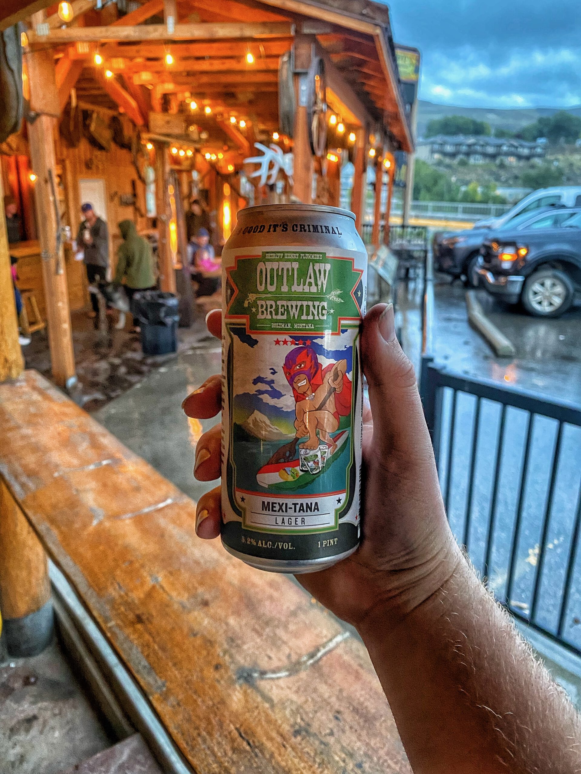 Hand holding a can of Outlaw Brewing Mexi-Tana Lager on a rainy evening in Gardiner, Montana.