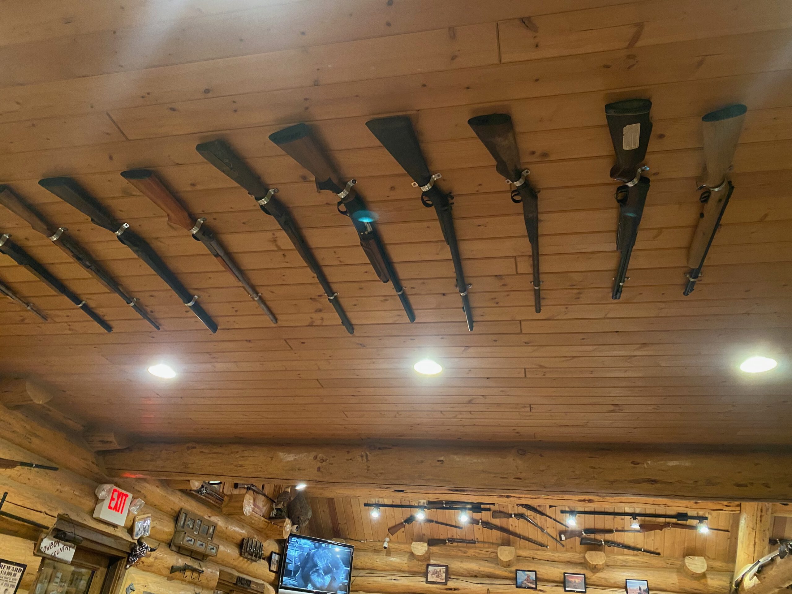 Western lodge interior with antique rifles mounted on a wooden ceiling at Cowboy’s Lodge and Grille near Yellowstone National Park