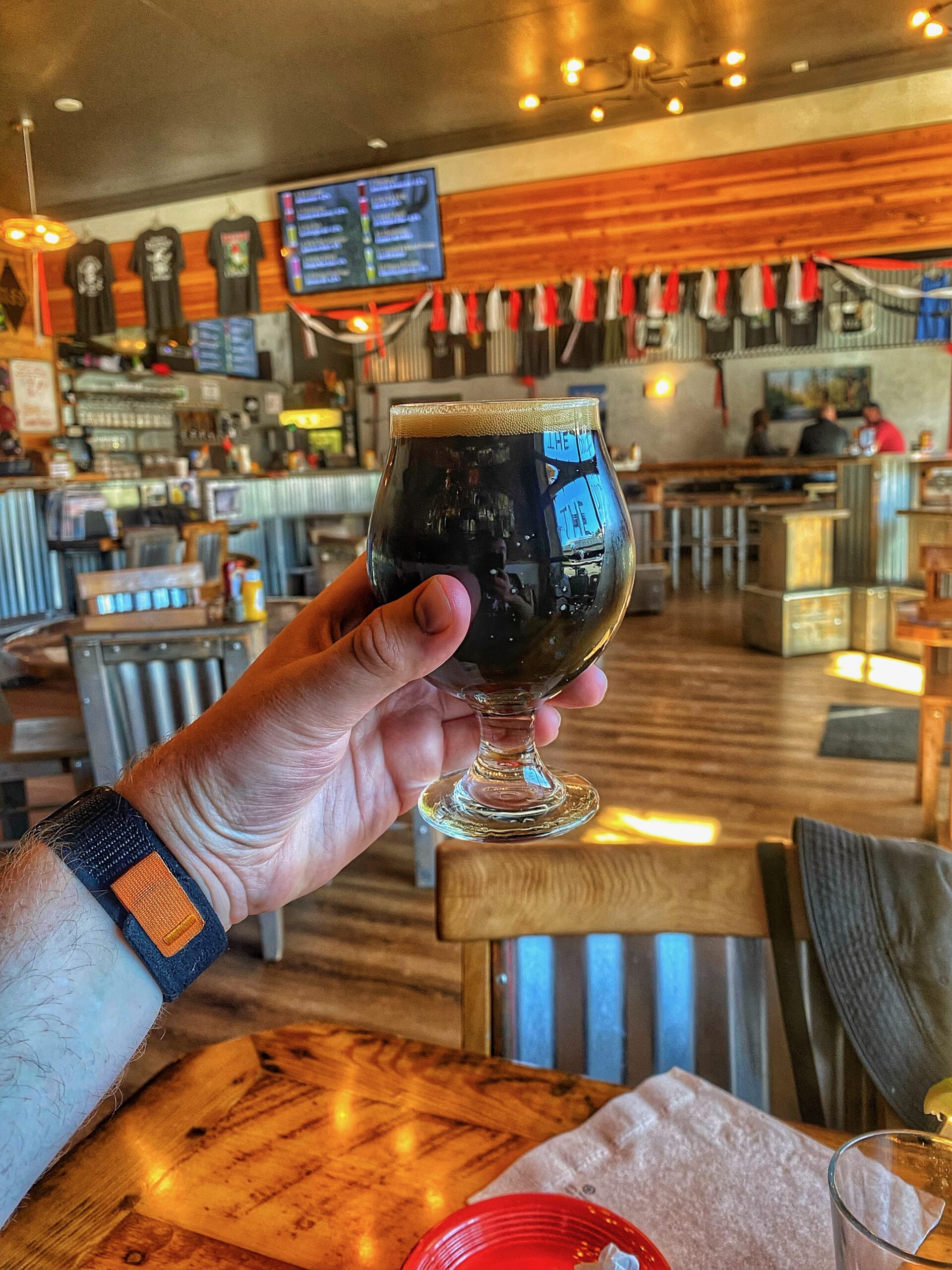 Dark craft stout served in a tulip glass inside 1188 Brewing Company in John Day Oregon, photographed in a warm rustic brewery interior with wooden tables and local decor. Timeuw is drinking in the United States of America, Timo van den Berg