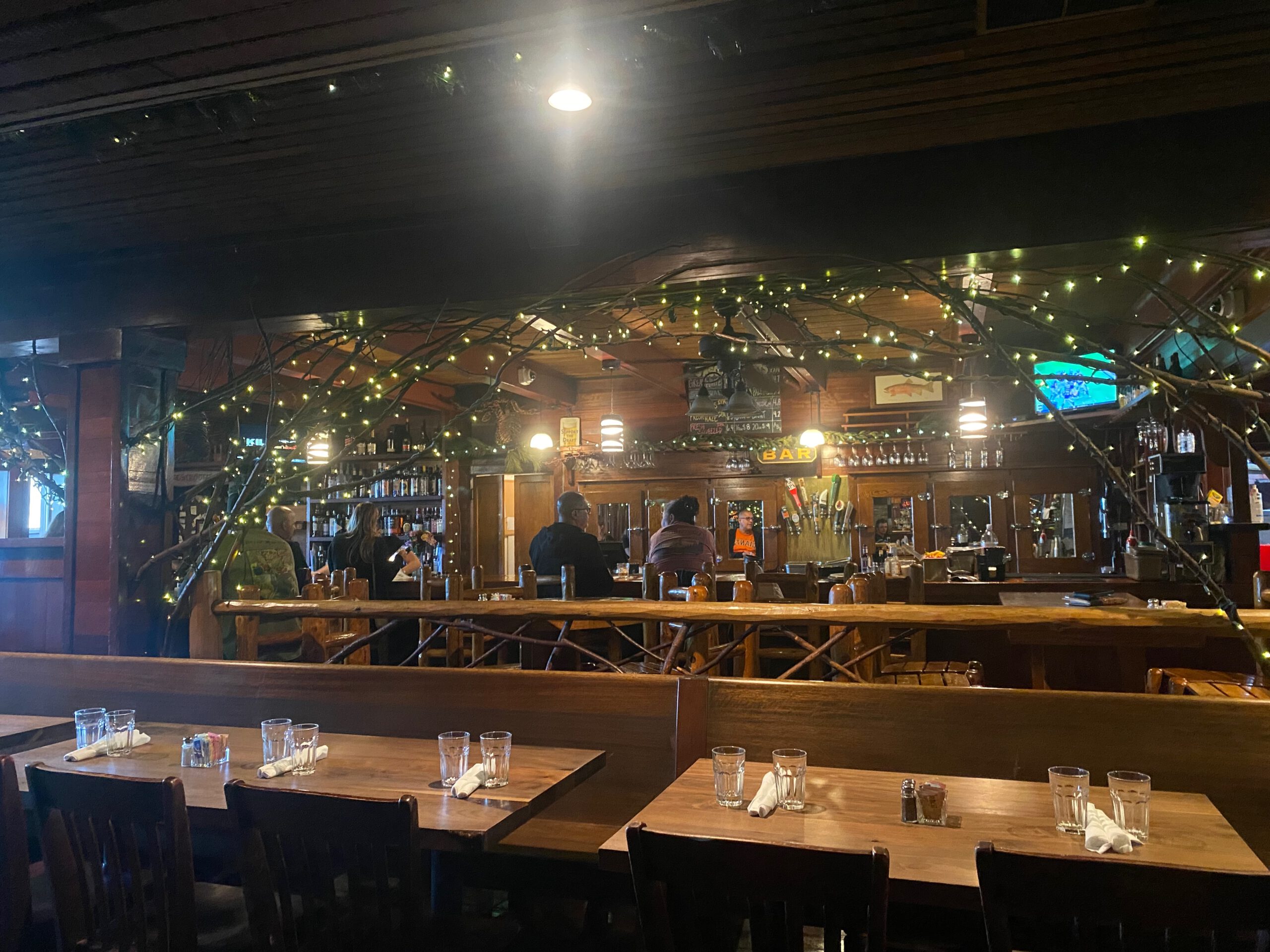Interior view of Jasons Beachside Grille Lake Tahoe showing the wooden bar, cozy lighting, and guests enjoying drinks inside the restaurant in Kings Beach, California.