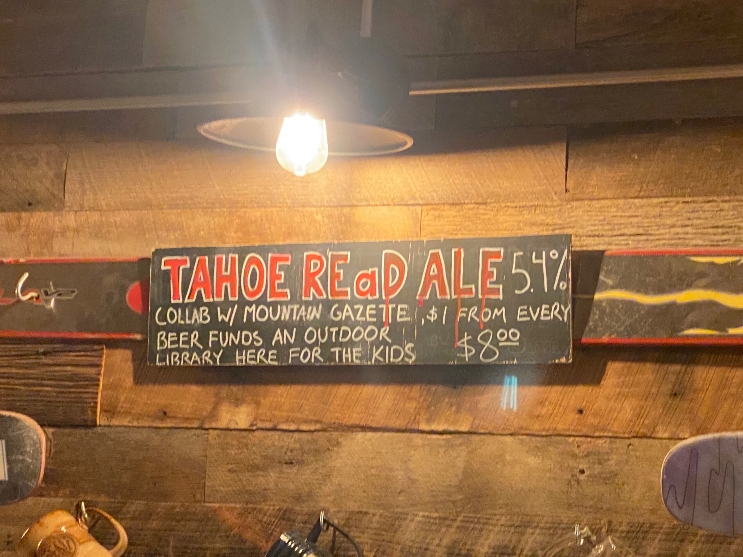Handwritten chalkboard sign showing Tahoe Red Ale 5.4 percent at Bear Belly Brewing Company in Kings Beach California, highlighting a local craft beer that supports a children’s outdoor library near Lake Tahoe