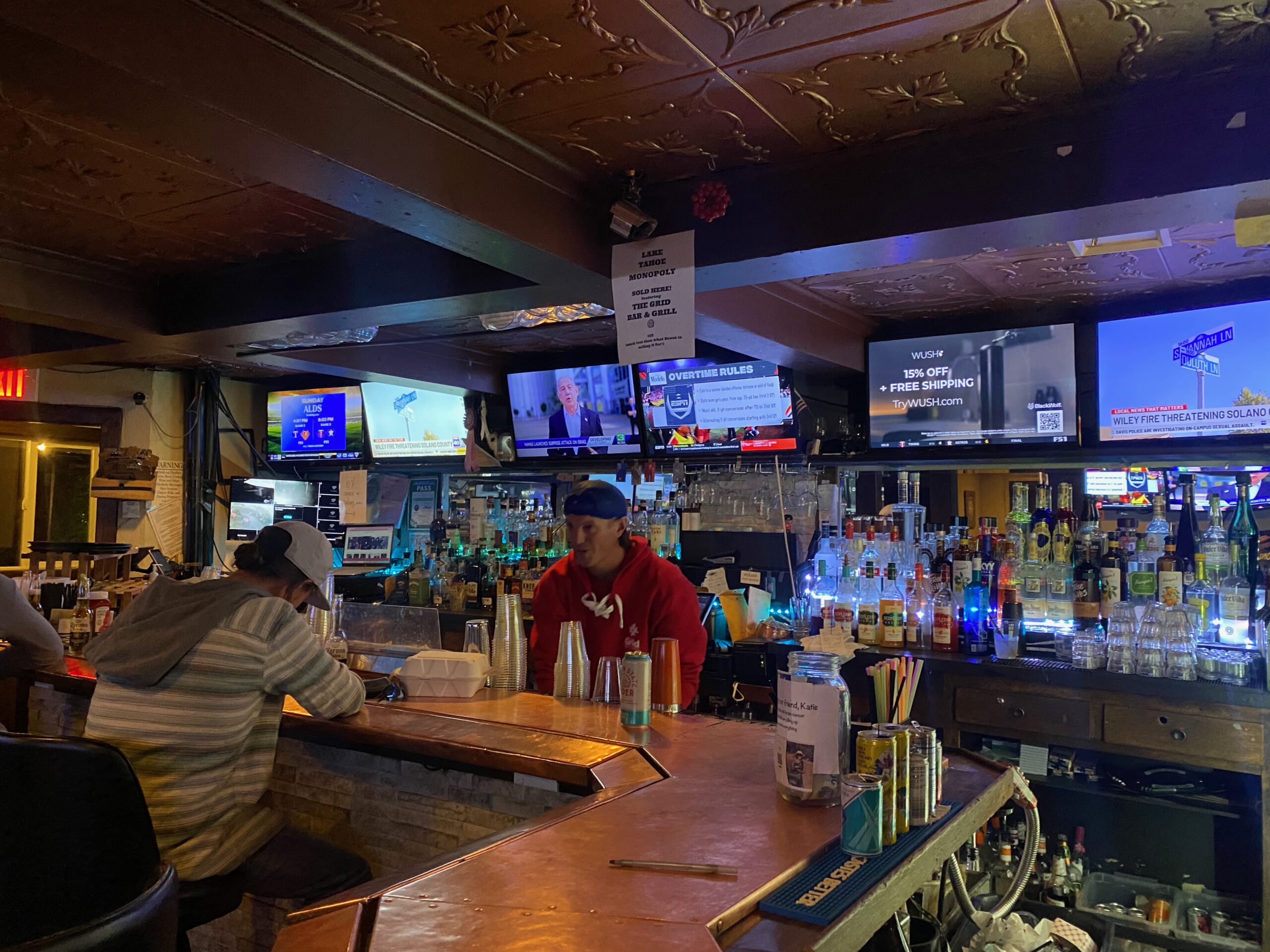 Bartender serving drinks behind the bar at The Grid Bar and Grill Lake Tahoe with bottles, taps and sports screens