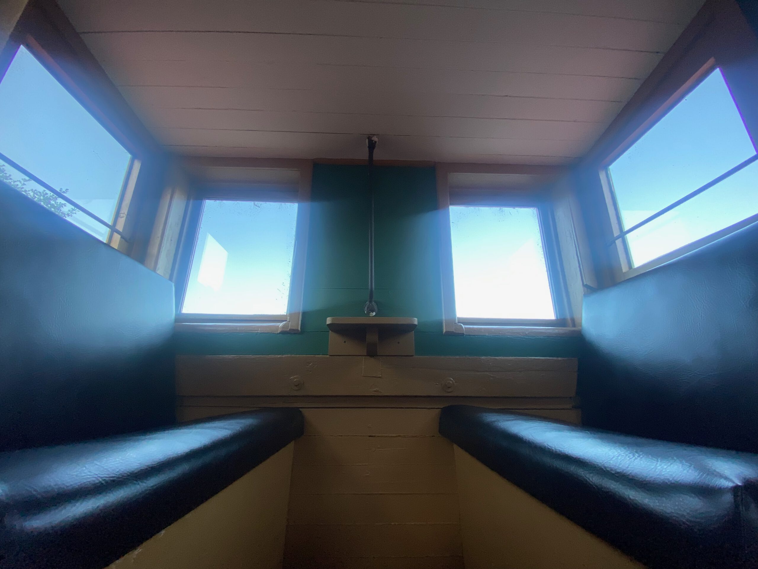 Interior view of the Vacation Station caboose cupola seating, original train benches and windows, historic Airbnb stay in Coulterville California