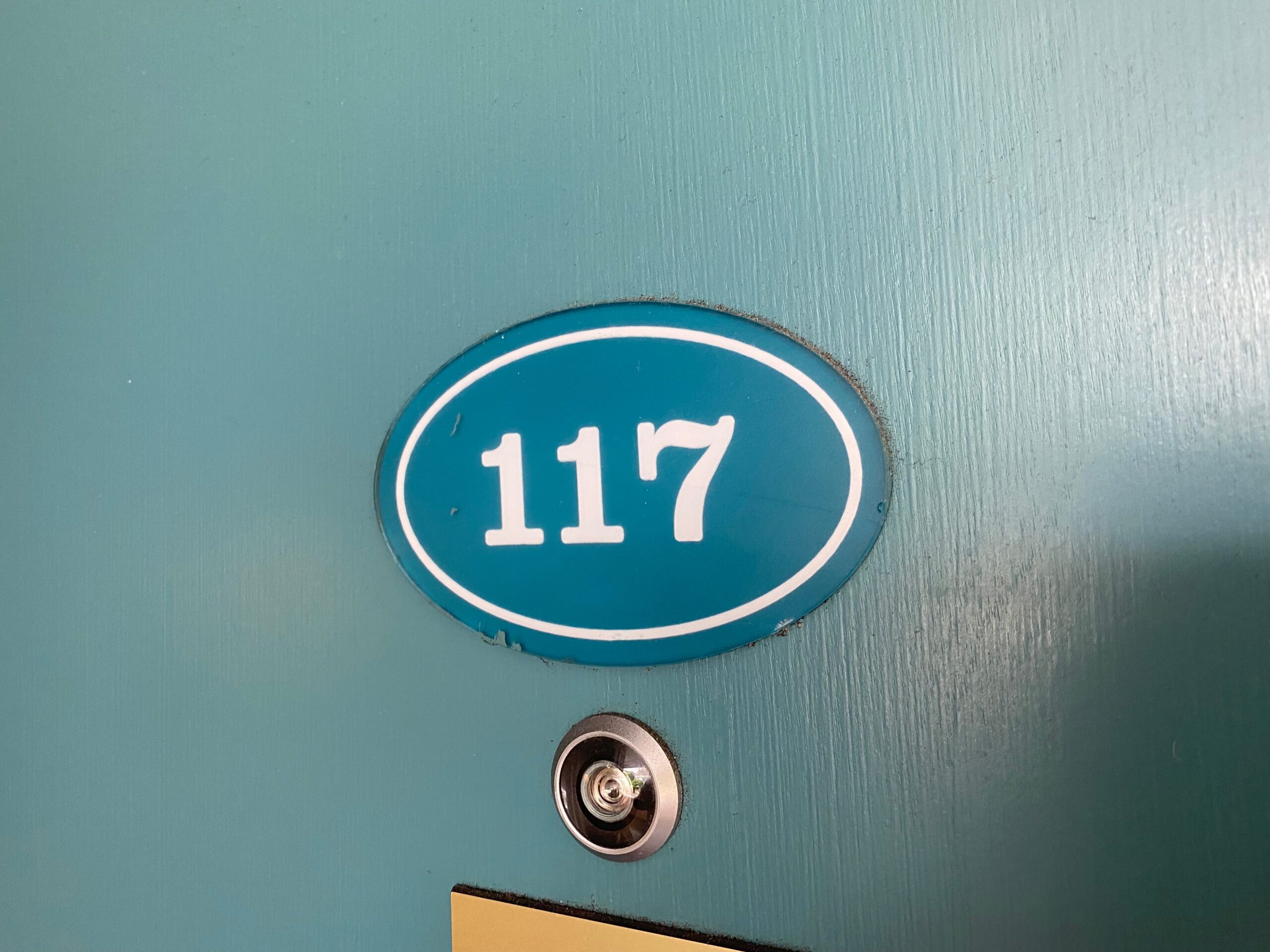 Town House Motel San Francisco room 117 door close up, teal painted motel door with vintage room number plaque and peephole