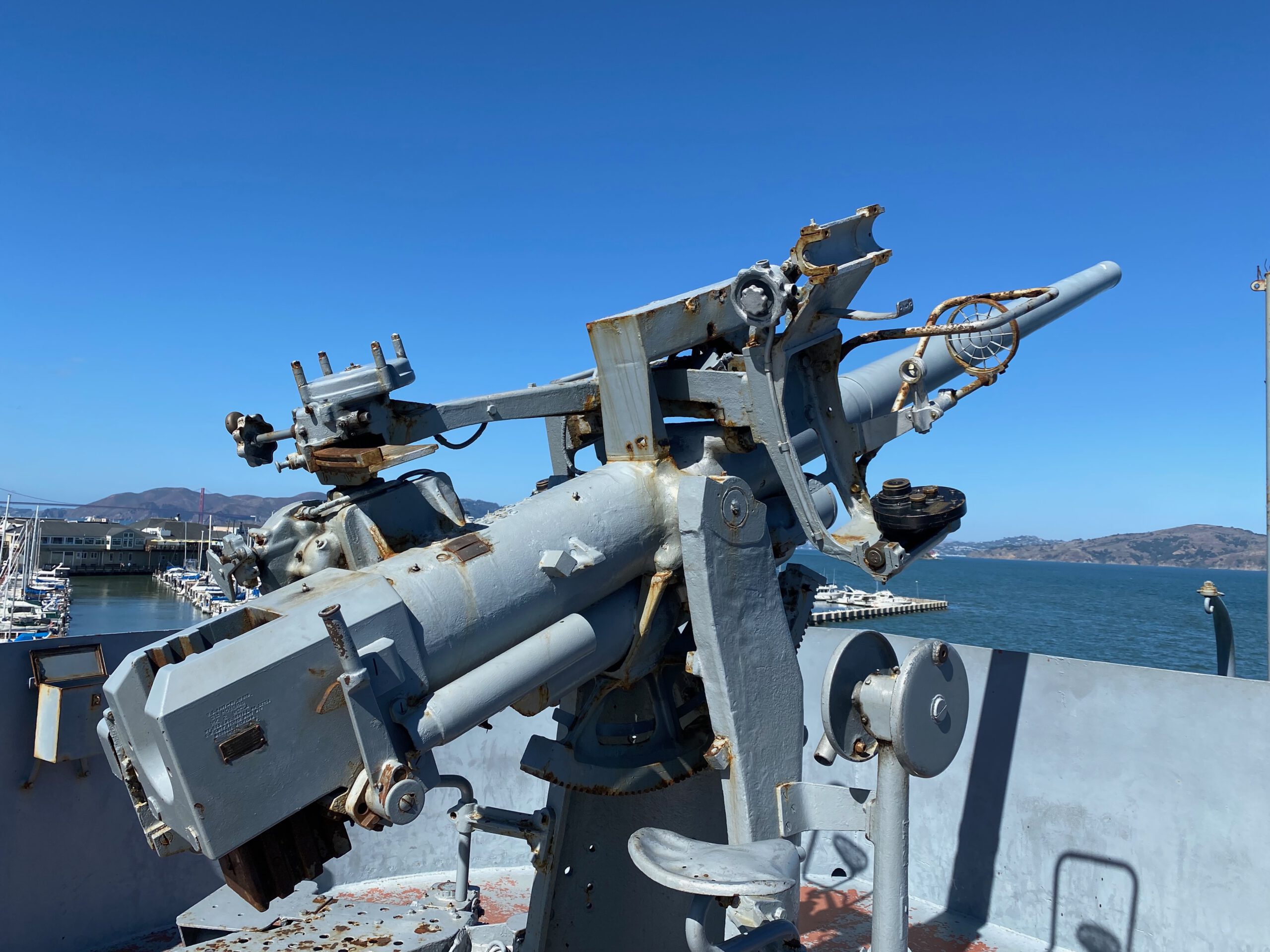 SS Jeremiah O'Brien close up of original World War II naval gun mount on deck, featuring mechanical details with San Francisco Bay in the background