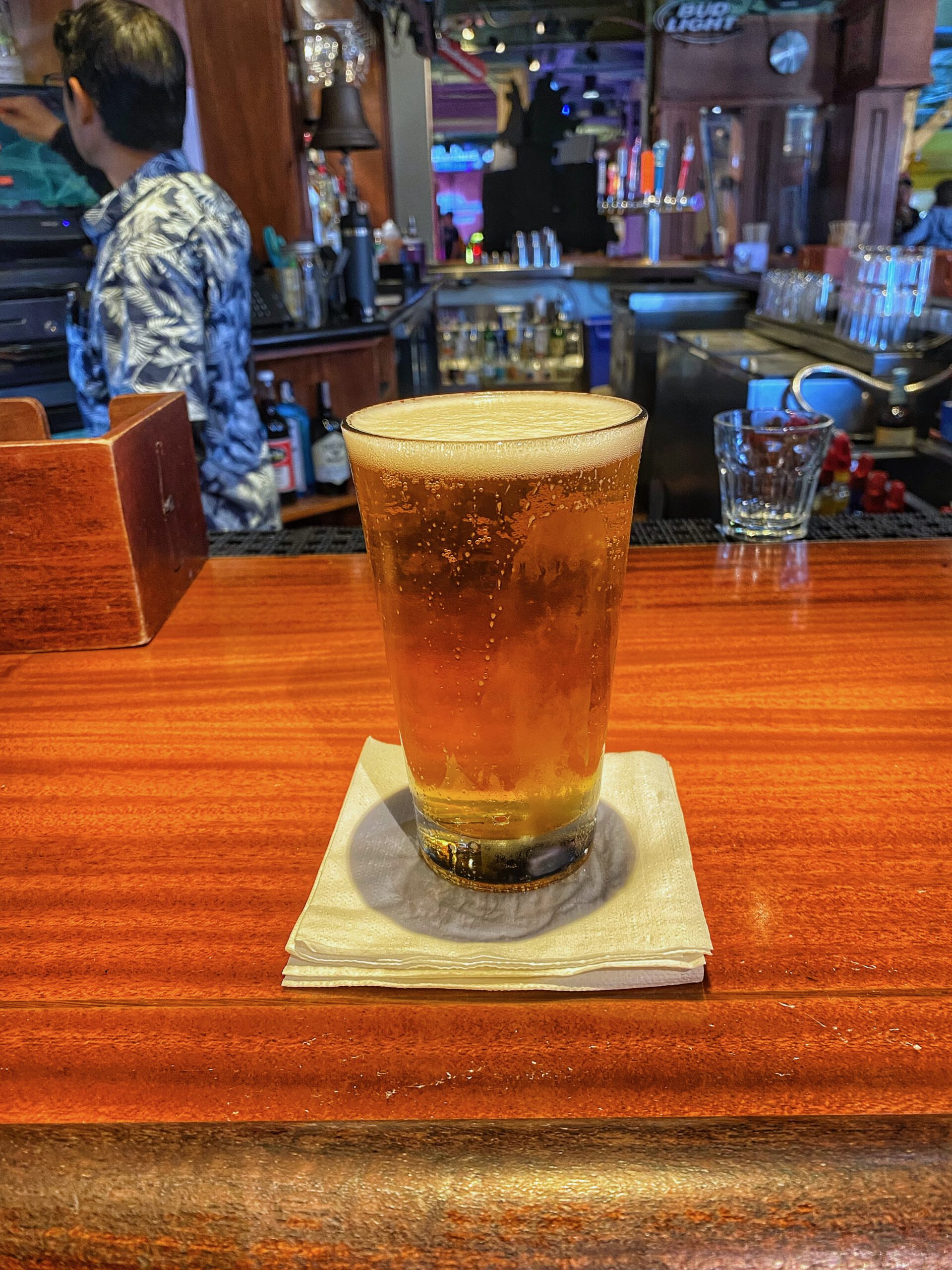 Cold draft beer served at the bar inside Players Sports Grill & Arcade on Pier 39 in San Francisco, shown on a wooden counter with beer taps, Bud Light signage, and a lively American sports bar setting in the background.