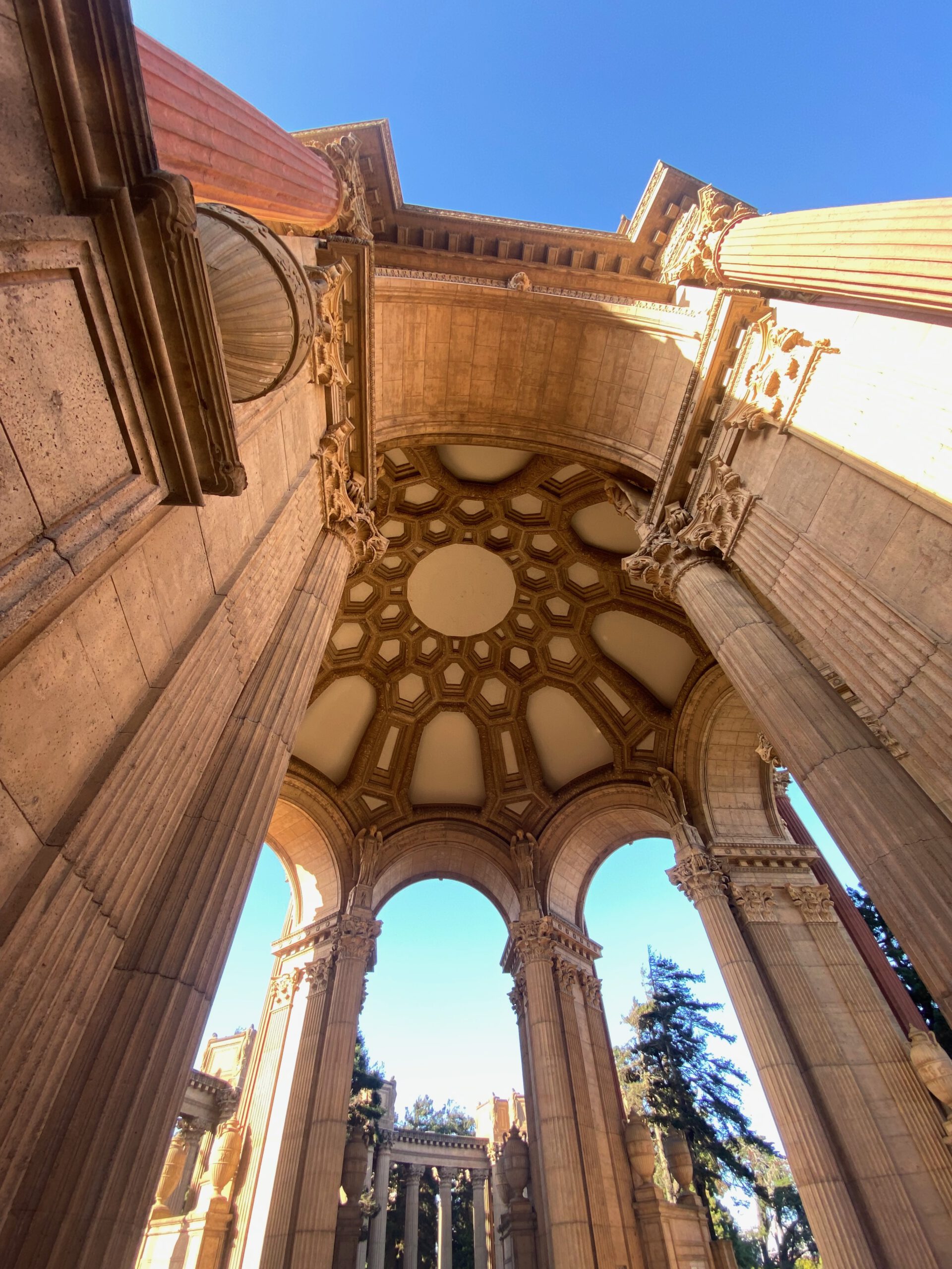 Palace of Fine Arts San Francisco rotunda interior viewed from below, showing the detailed coffered dome, classical arches, and towering columns against a clear blue sky
