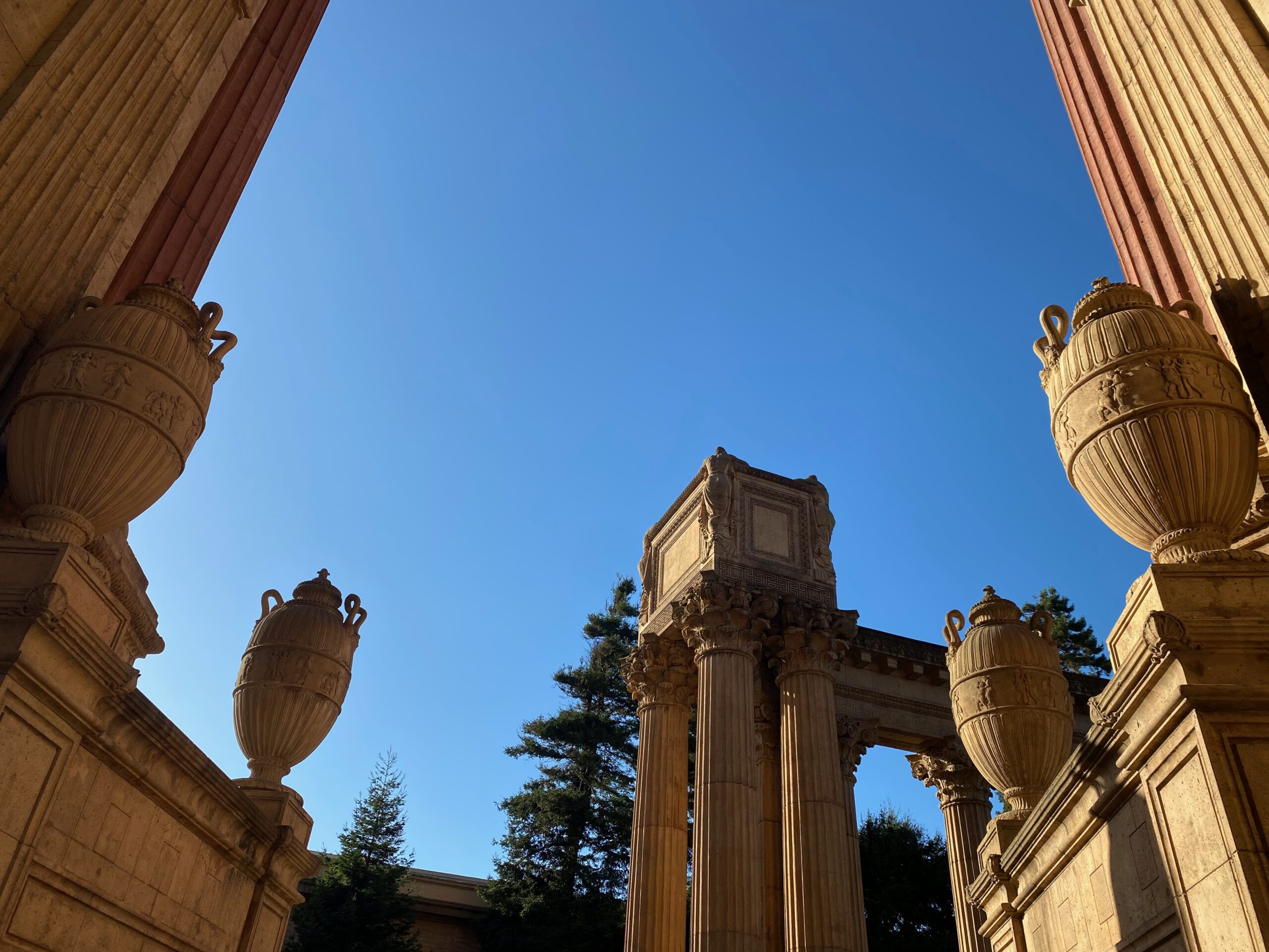 Palace of Fine Arts San Francisco colonnade with ornate urns and classical columns, framed by blue sky and warm stone details in the Marina District