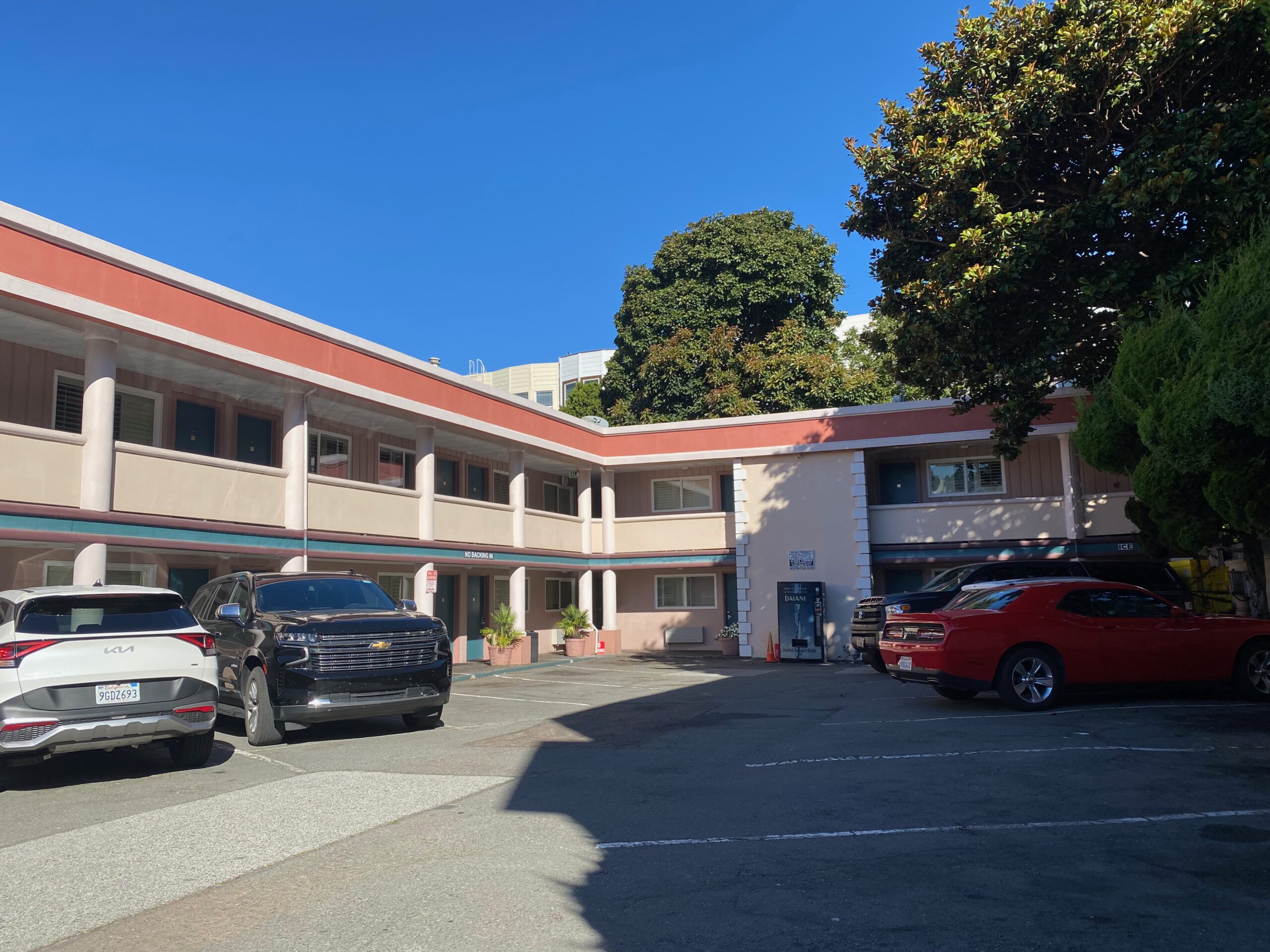 Town House Motel San Francisco inner courtyard and parking area, classic two story roadside motel with parked cars, sunny day in the Marina District. It shows the parking situation of the motel