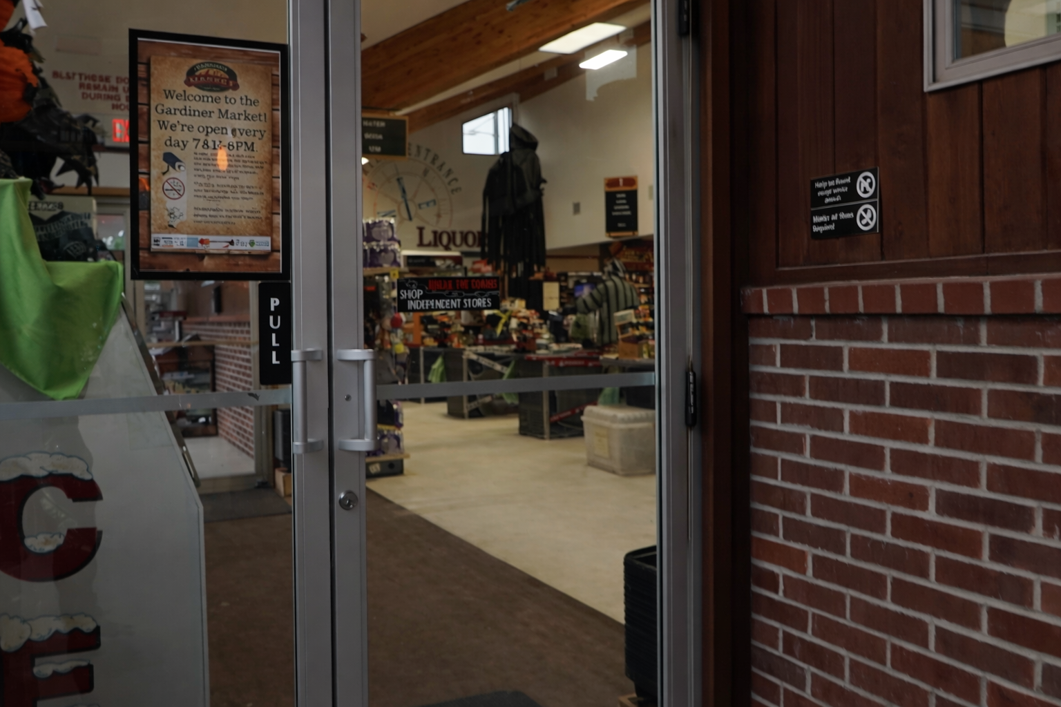 Entrance of Gardiner Market in Gardiner MT, with clear store signage, opening hours, and a welcoming view into the grocery store
