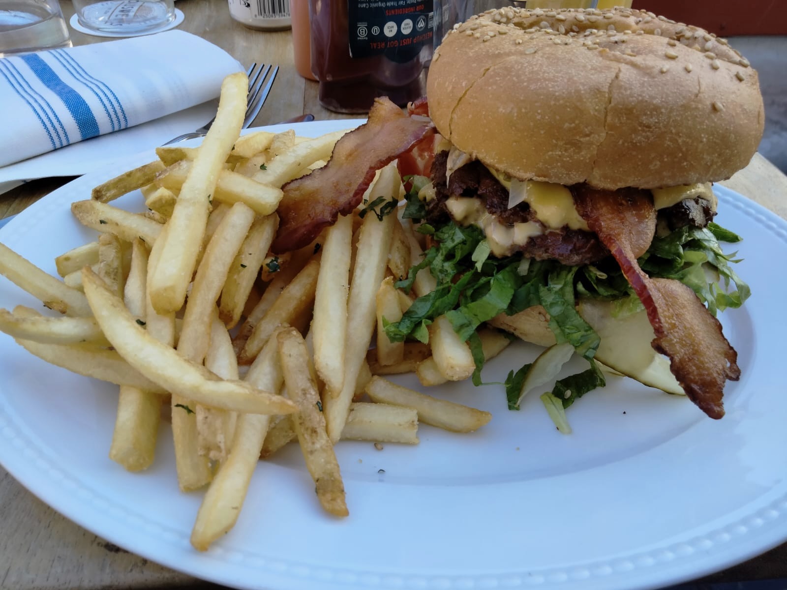 Premium bacon cheeseburger with melted cheese and crispy fries at Causwells San Francisco, served outdoors in the Marina District