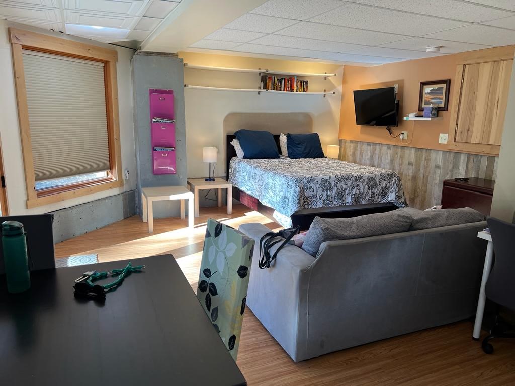 Cozy sleeping and living area inside a Lake Tahoe studio rental, featuring a comfortable bed, sofa, workspace and warm natural light in a quiet Tahoe Vista interior.