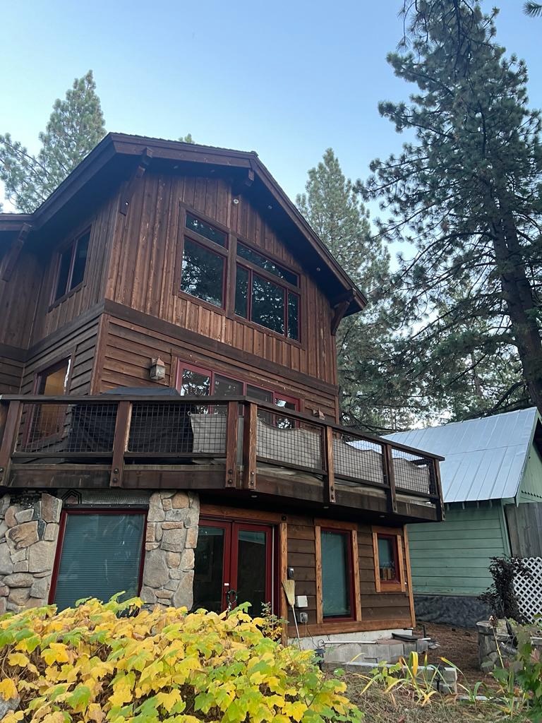 Exterior view of a rustic wooden cabin surrounded by pine trees in Tahoe Vista, showcasing a quiet residential setting of a Lake Tahoe studio rental near nature and forest scenery.