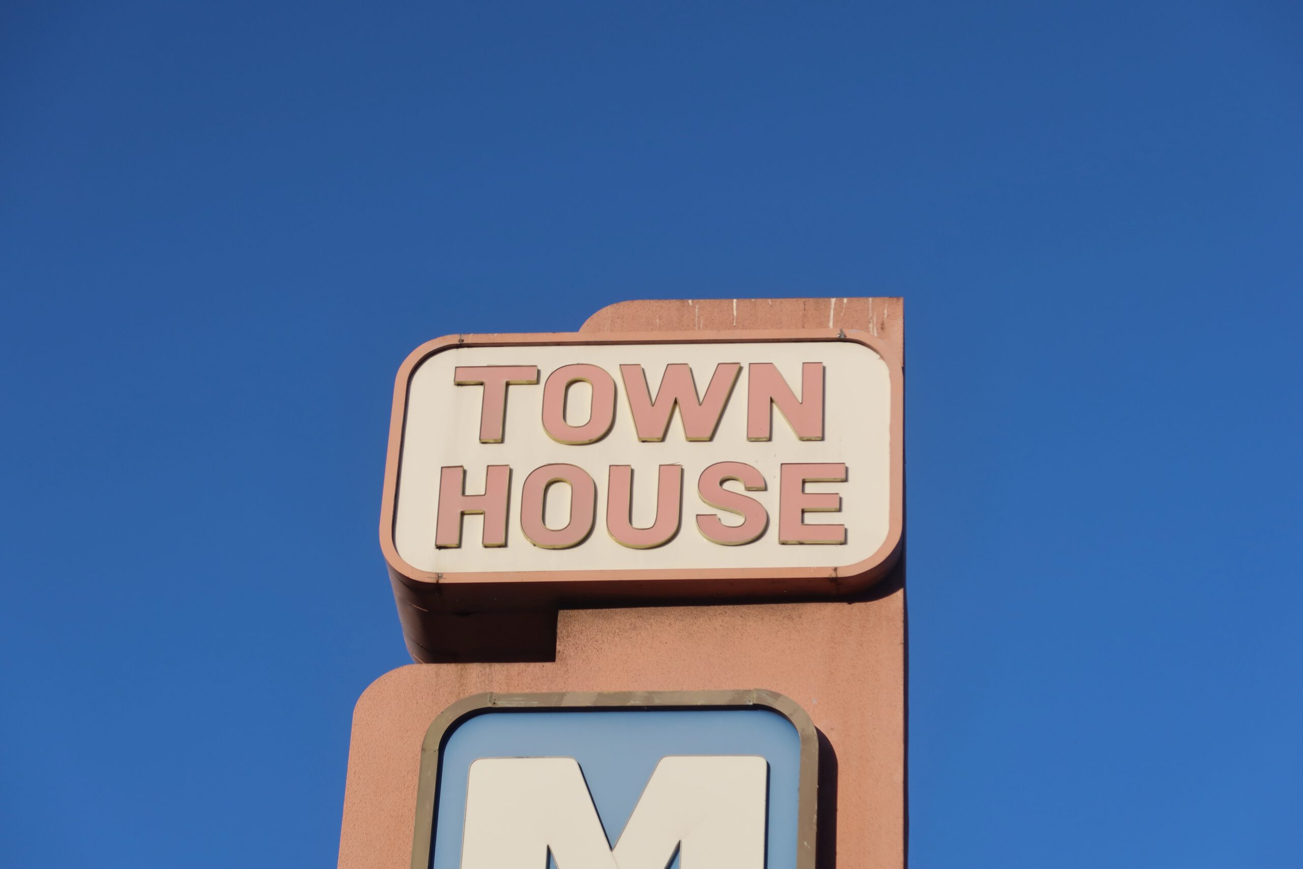 Town House Motel San Francisco sign close up against a clear blue sky, showing the vintage roadside motel branding on Lombard Street