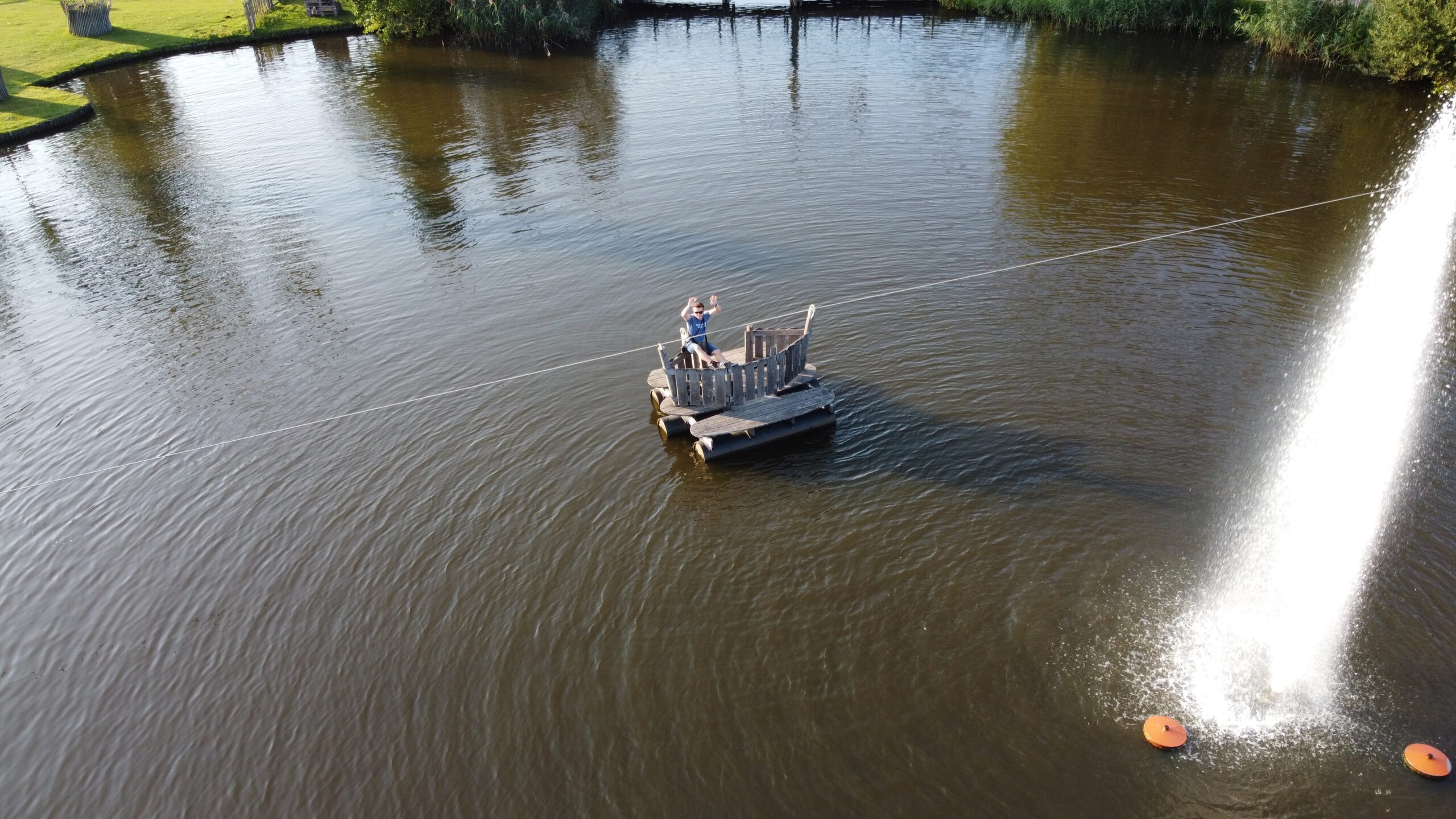 Center Parcs De Huttenheugte Day Visit aerial drone shot of Peter Smit standing on a wooden raft on the lake near the fountain at the park in Dalen, Drenthe.