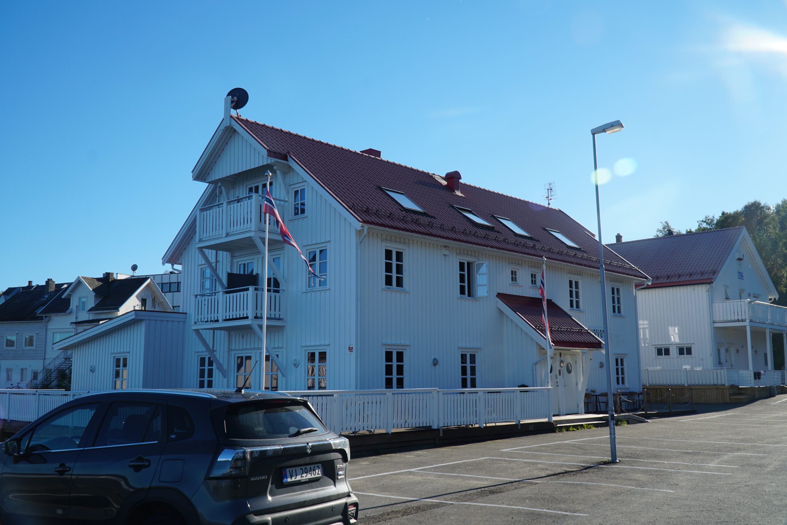 Lødingen Brygge Hotel Norway seen from the waterfront, white wooden hotel building with balconies, clear blue sky and fjord atmosphere in Northern Norway