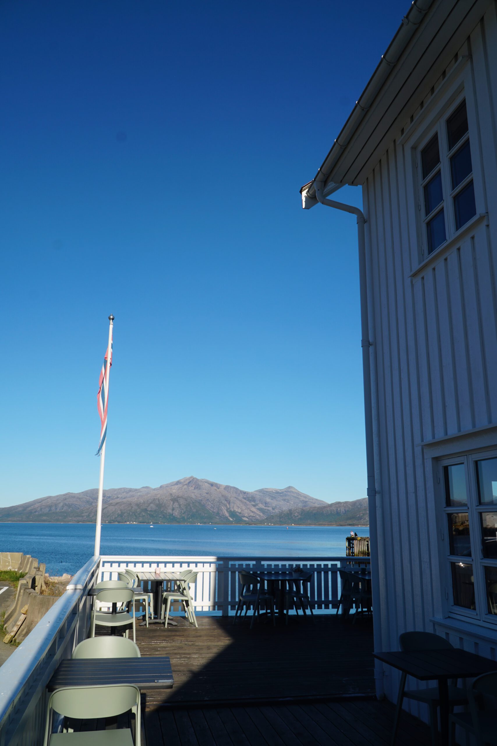 Terrace at Lødingen Brygge Hotel Norway overlooking the fjord, outdoor seating area with Norwegian flag and mountain views in Northern Norway