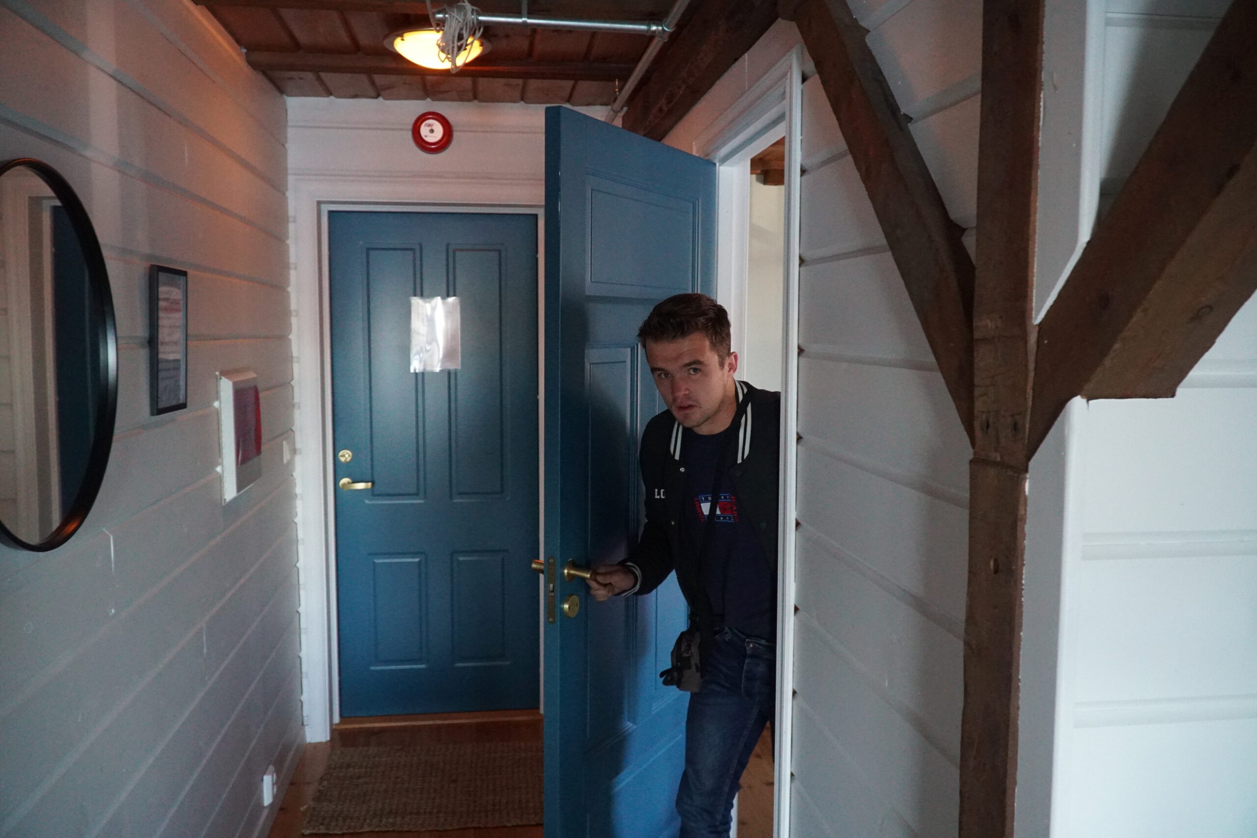 Guesthouse hallway with blue wooden doors, exposed beams and Scandinavian interior design in Lødingen Norway