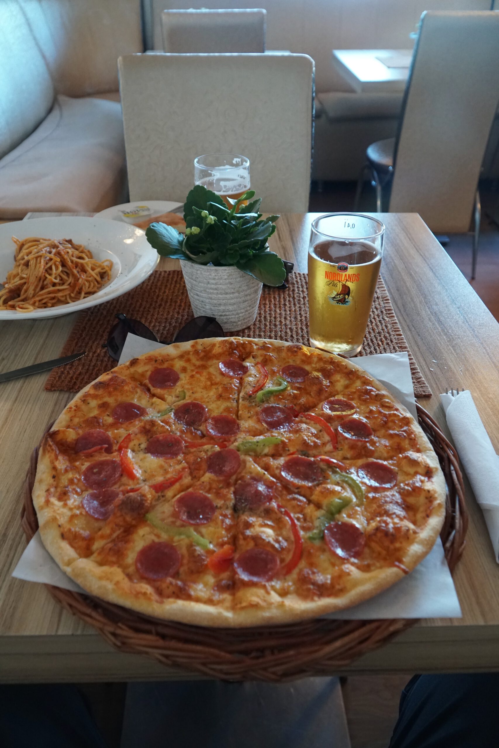 Mama Rosa Lødingen pizza with pepperoni and bell peppers served alongside local Nordlands beer and spaghetti bolognese inside the restaurant